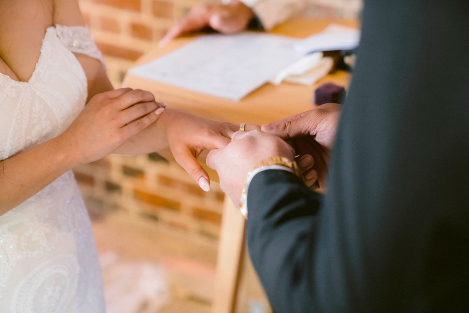 Close-up view of wedding couple's hands during their wedding ceremony vow exchange.