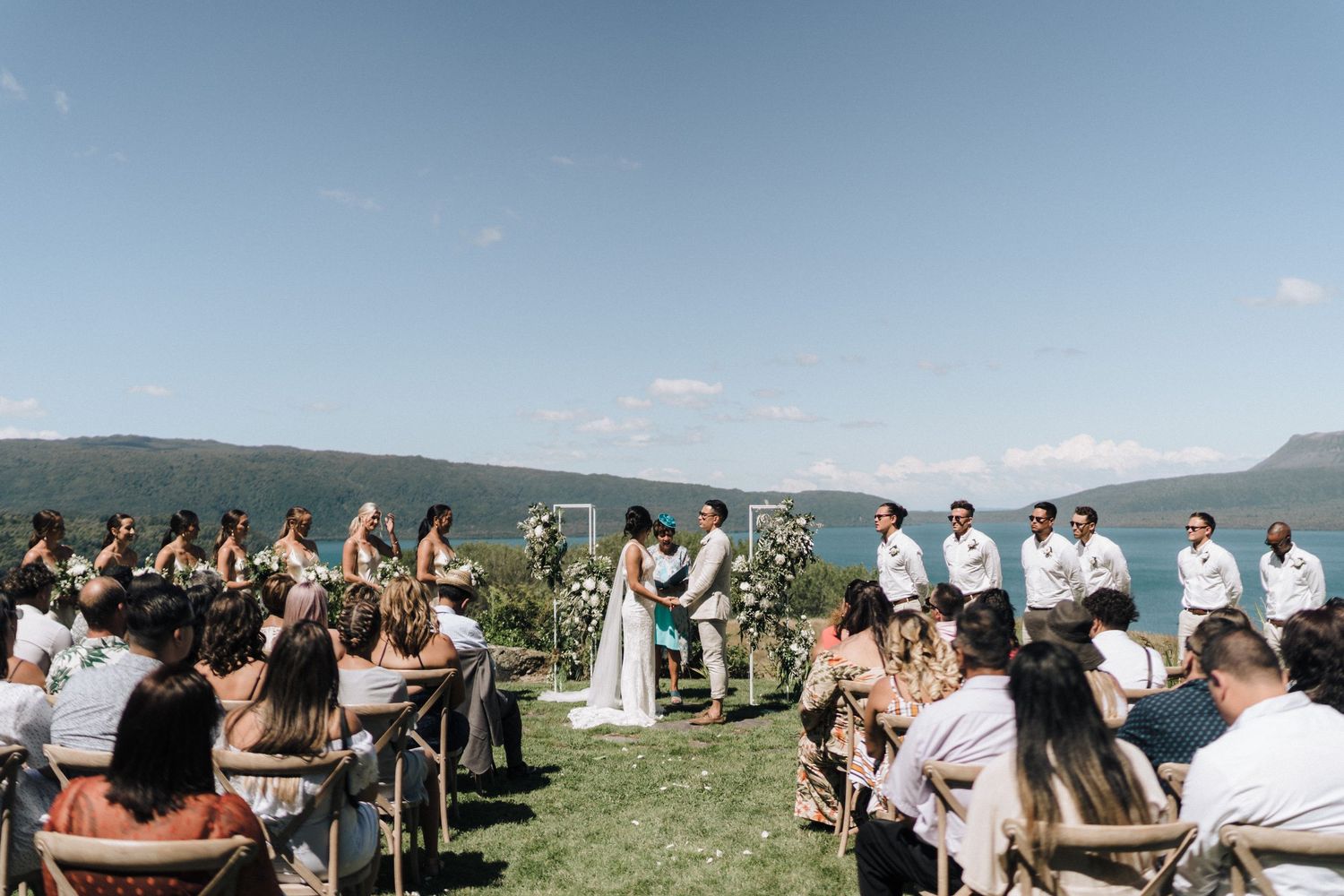 Mountain wedding ceremony with panoramic views and guests seated in white chairs on a scenic overlook.