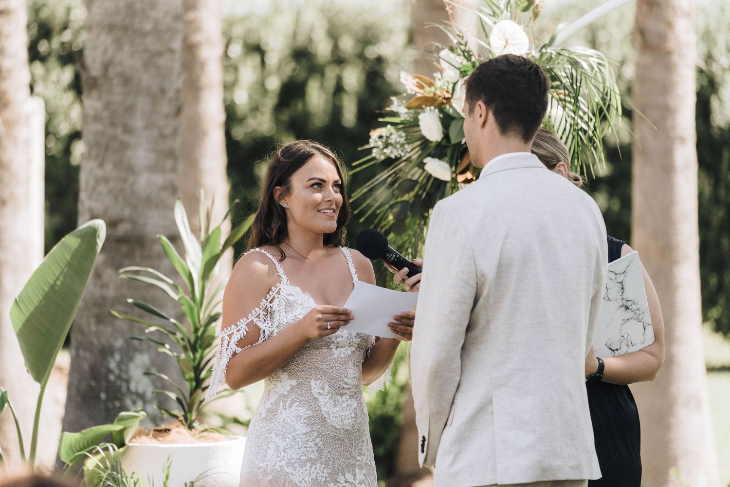Wedding ceremony moments captured in a tropical palm tree setting.