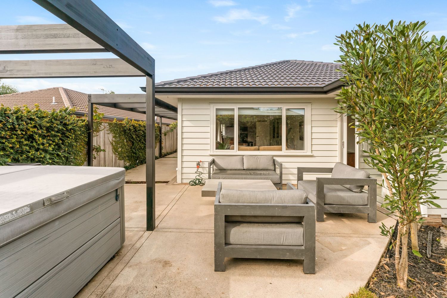 Exterior deck and seating area with grey wooden benches against cream-colored house siding.