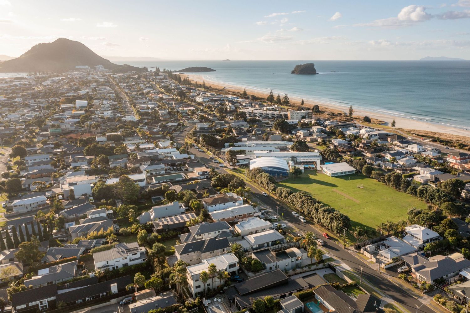 Panoramic aerial view of Mount Maunganui beachfront with coastal homes and ocean views during daytime.