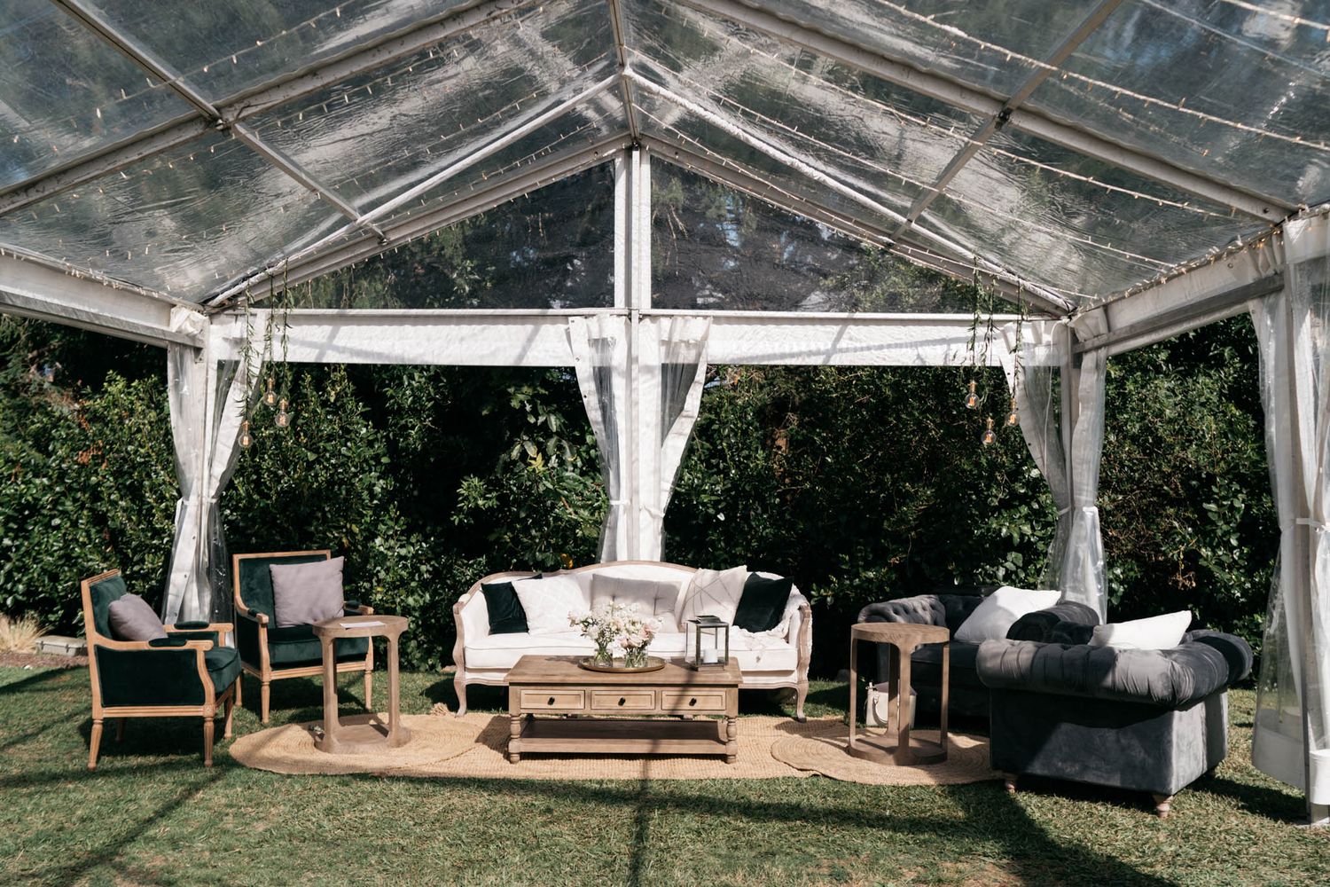 Elegant white-draped outdoor tent pavilion with comfortable seating arrangements set up for an upscale event or celebration.