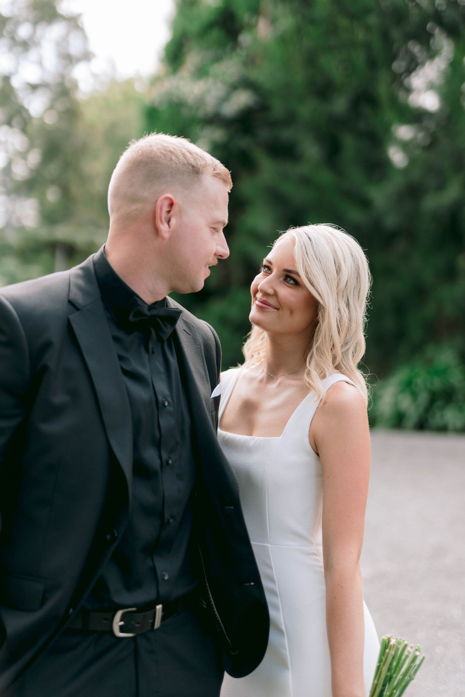 A loving couple share romantic moments outdoors in formal attire against a serene natural backdrop.