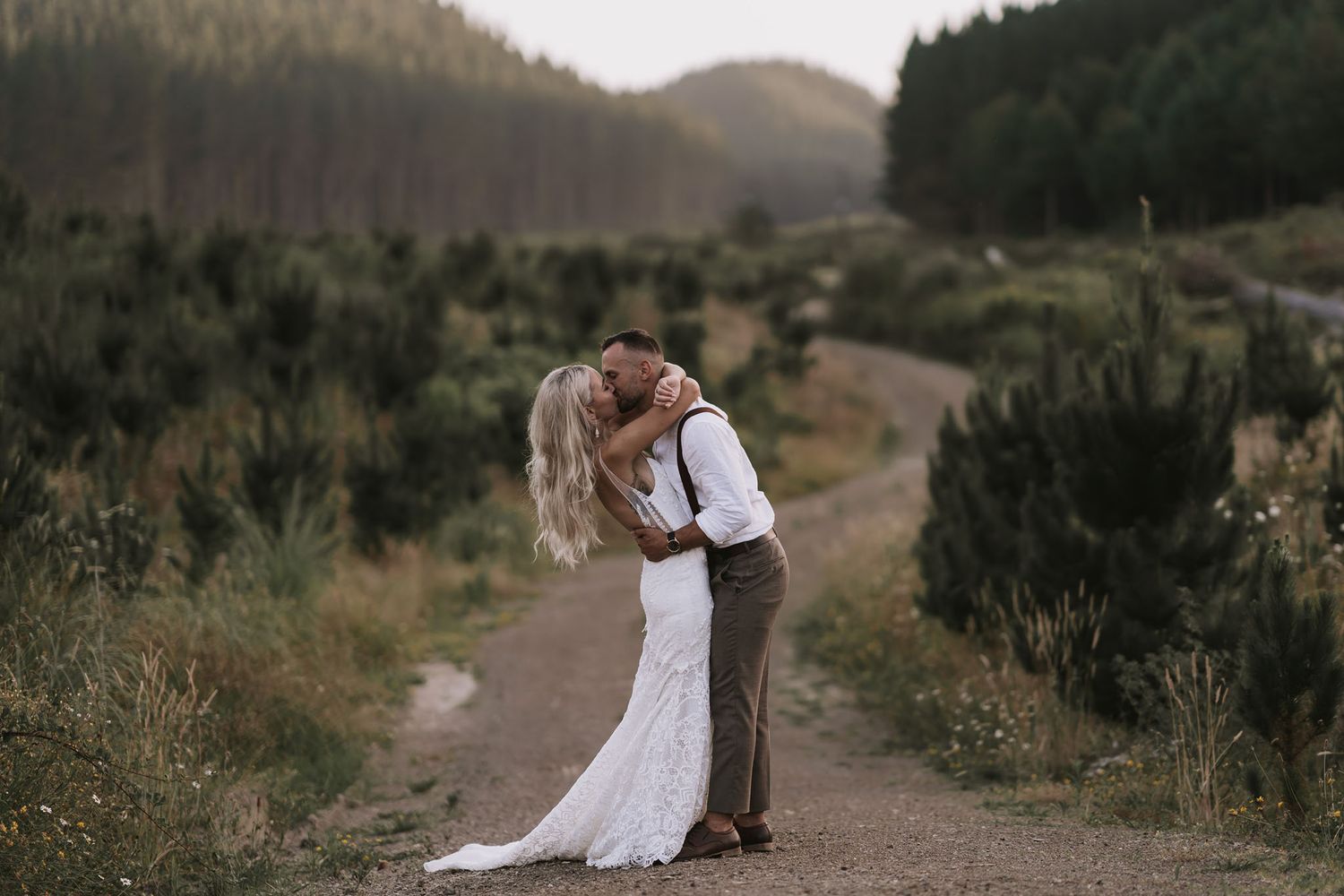 Couple embraces and kisses during outdoor mountain engagement photo session at golden hour.