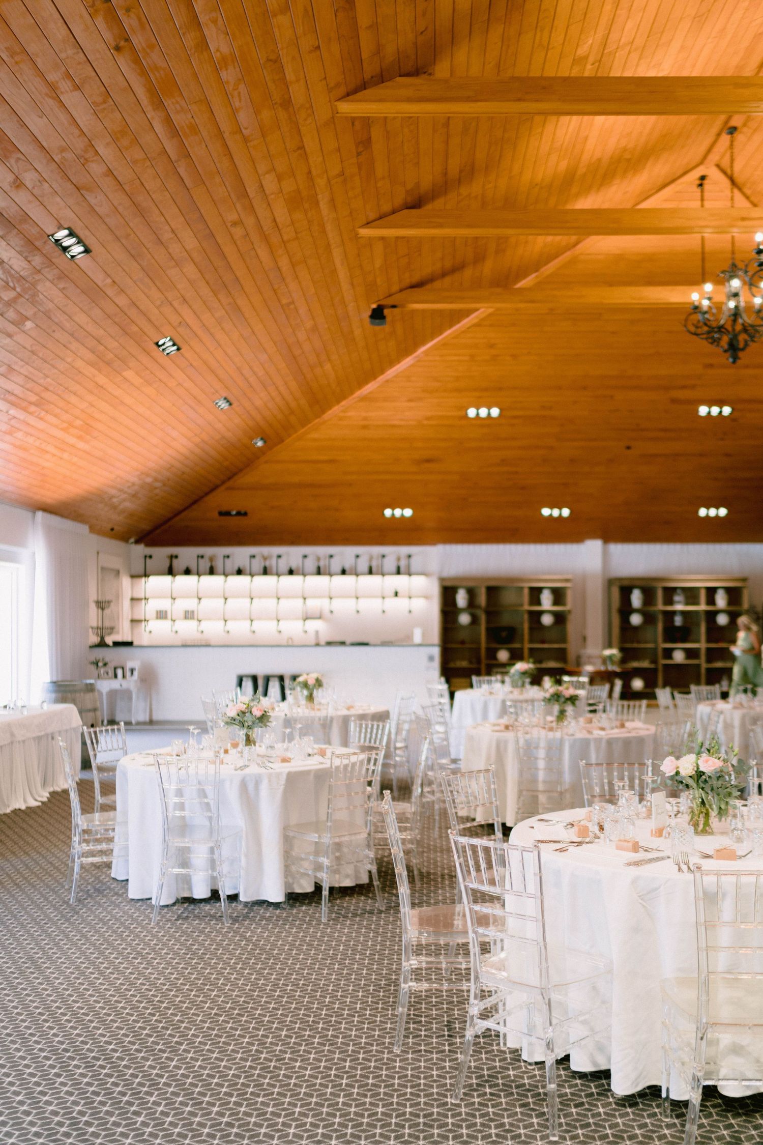 Elegant wedding reception venue with wooden ceiling beams and white table settings.