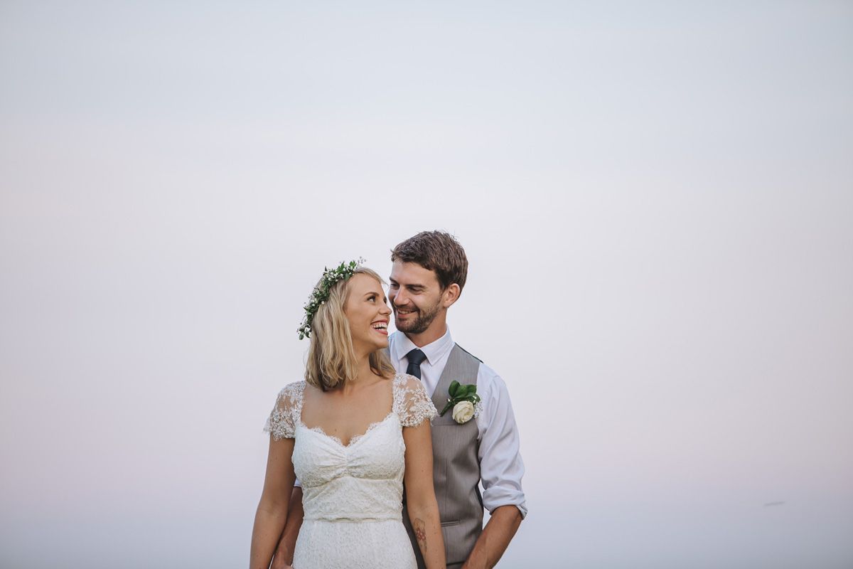 A romantic sunset wedding portrait shows the couple in elegant attire against a soft purple sky.