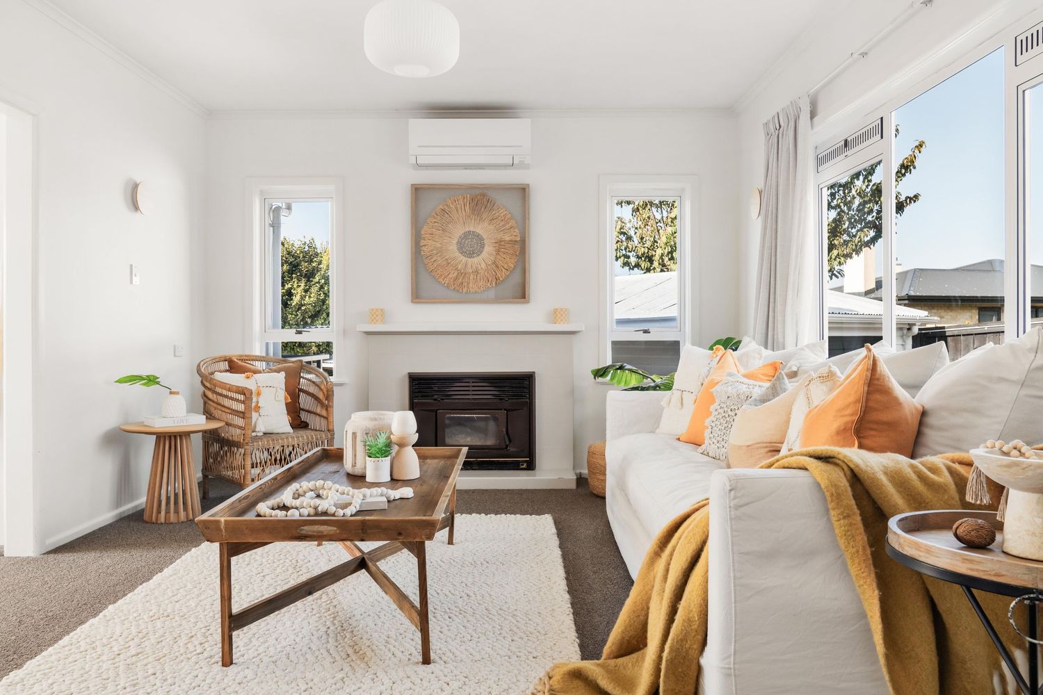 Bright coastal living room with fireplace, beige sofa, and orange accent pillows.