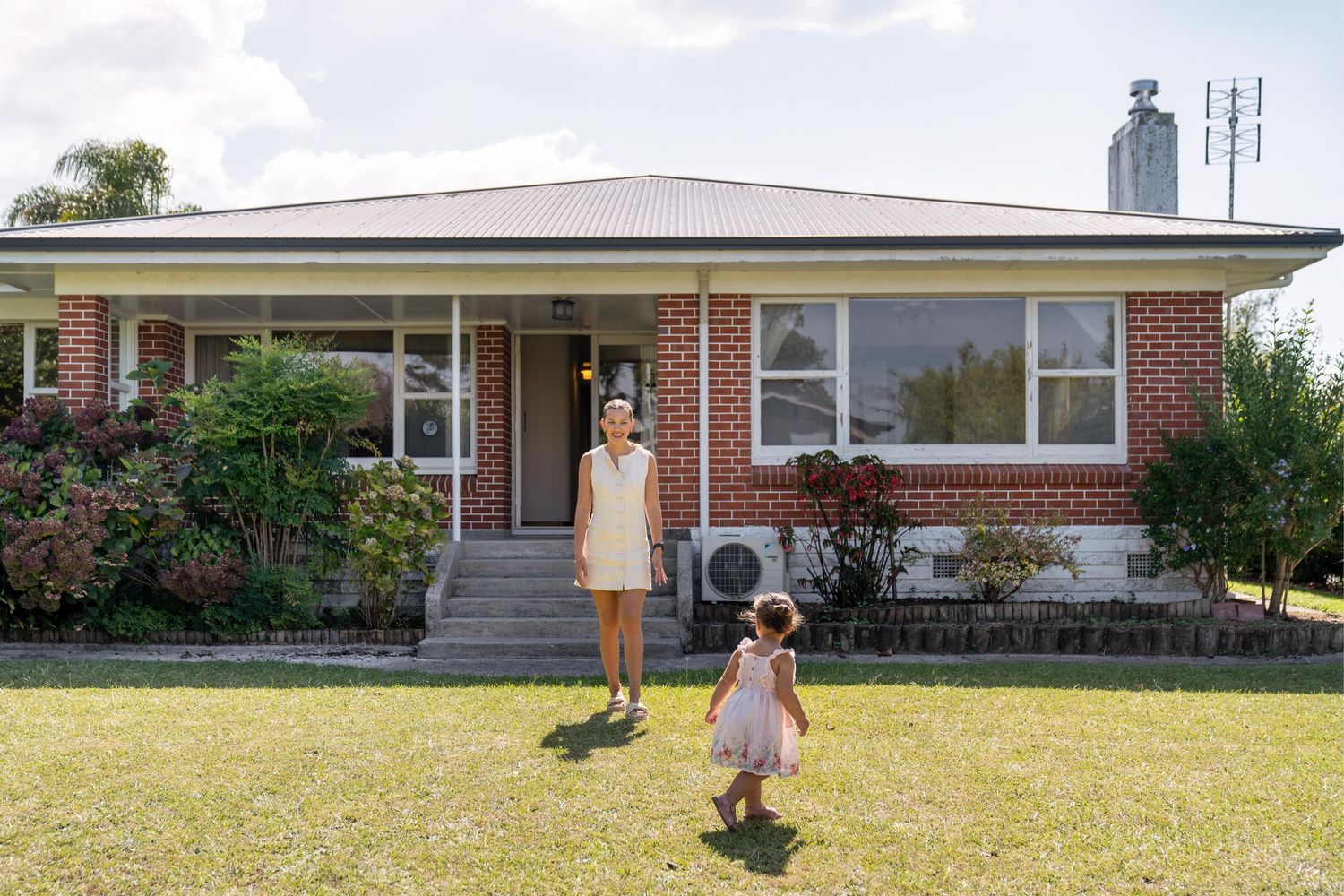 Panoramic view of a single-story brick ranch house with a gray roof and neatly maintained lawn.
