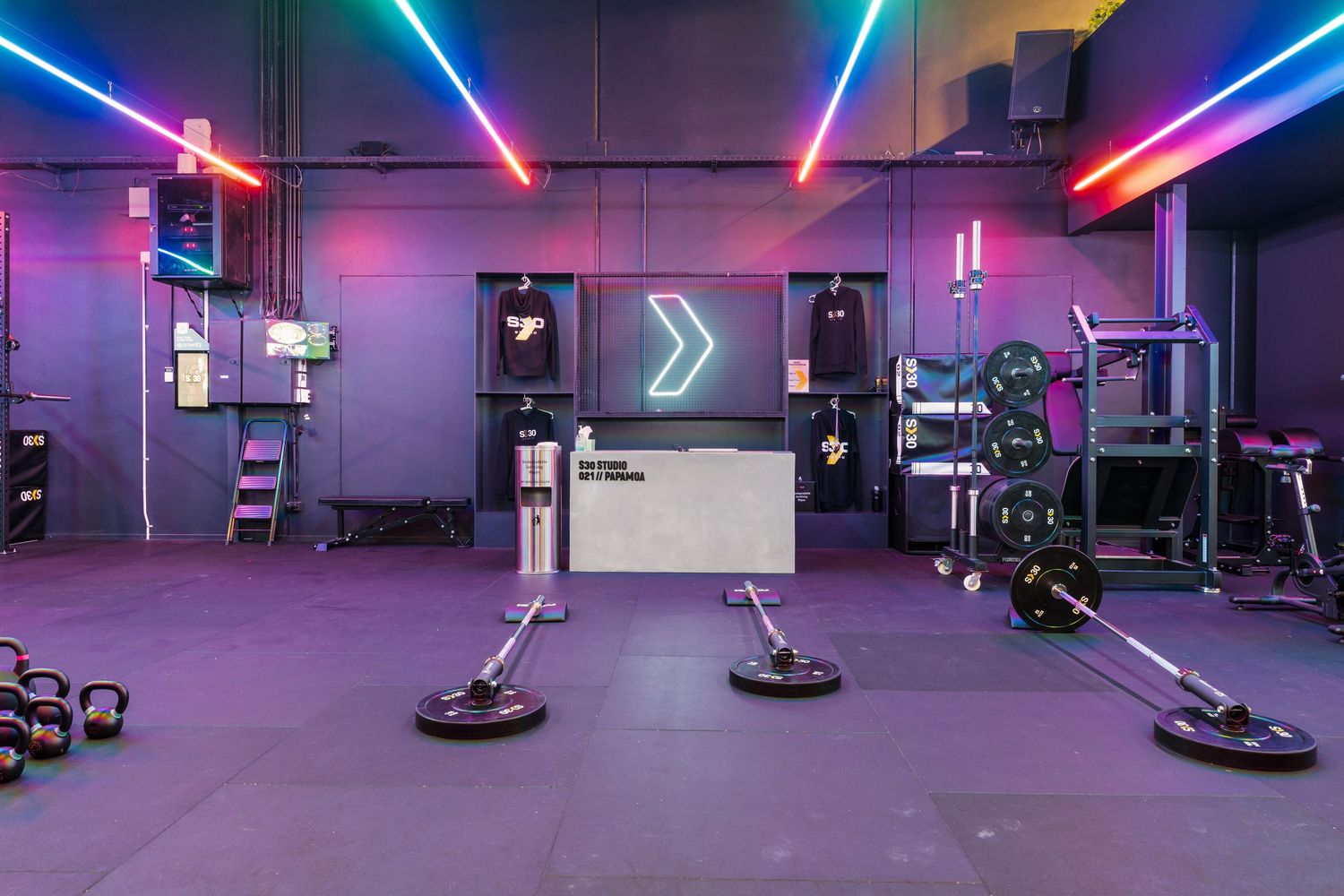 Functional training area with exercise platforms and equipment illuminated by neon lighting and arrow signage.