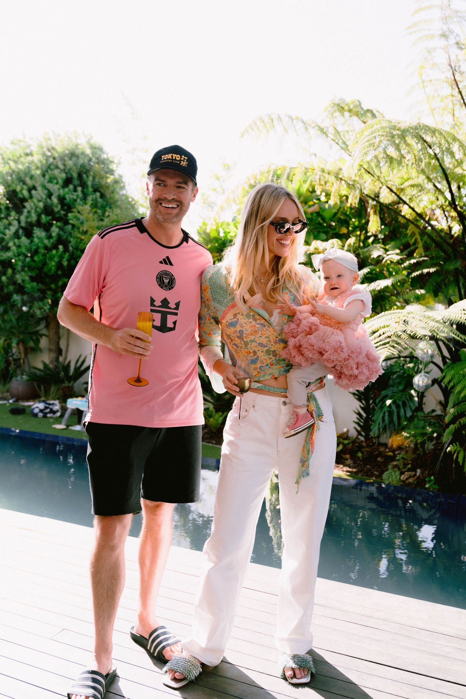 Casual outdoor gathering with people wearing summer attire near a swimming pool.