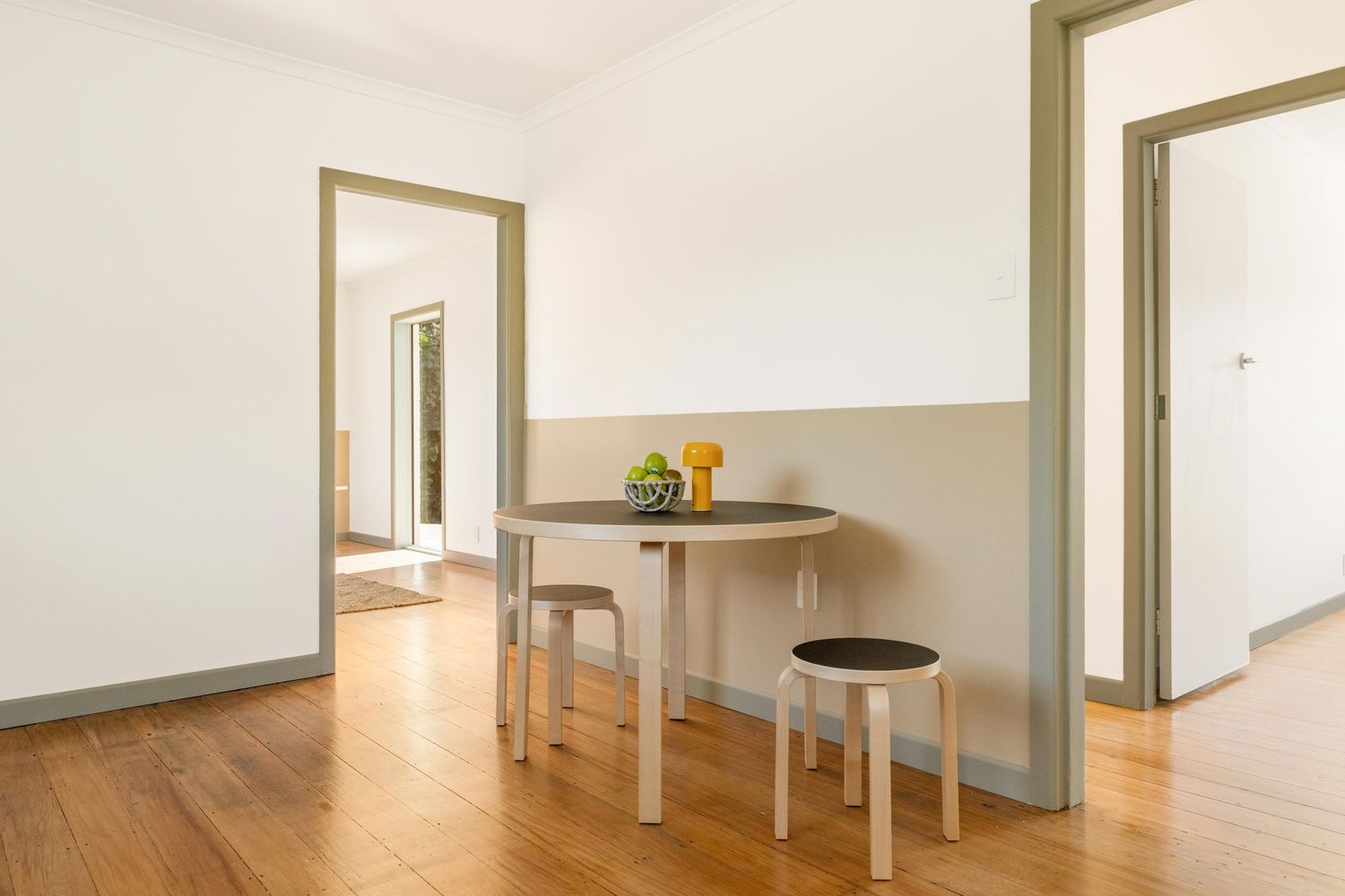 Minimalist wood table with clean lines and white legs positioned against a neutral-toned wall.