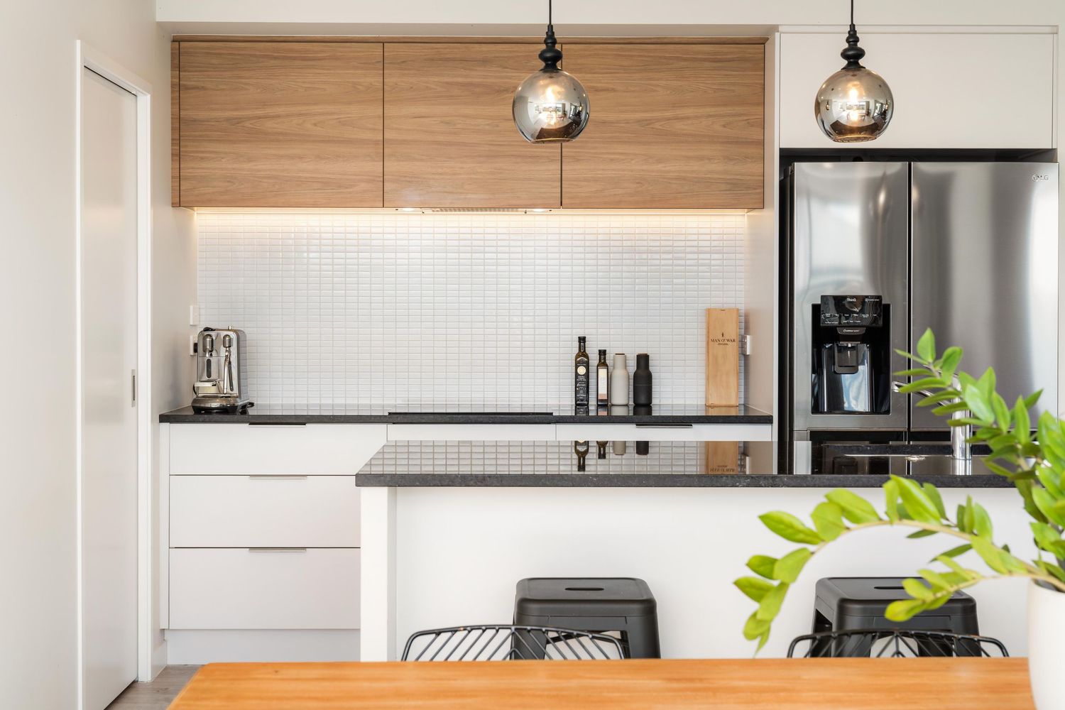 Sleek kitchen design with wood accents, white cabinets, stainless appliances and indoor plants.