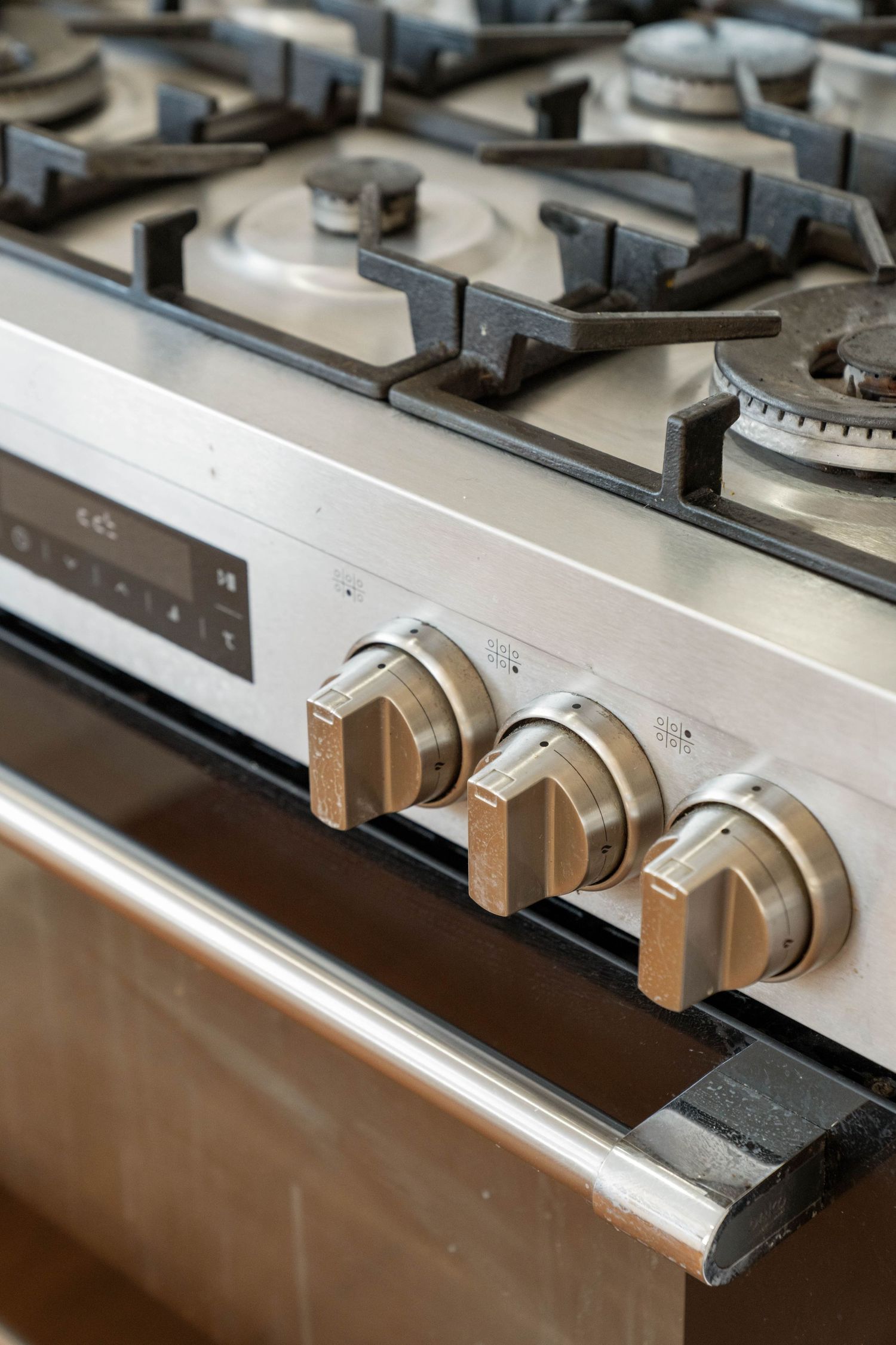 Close-up of stainless steel gas stovetop with control knobs and burners.