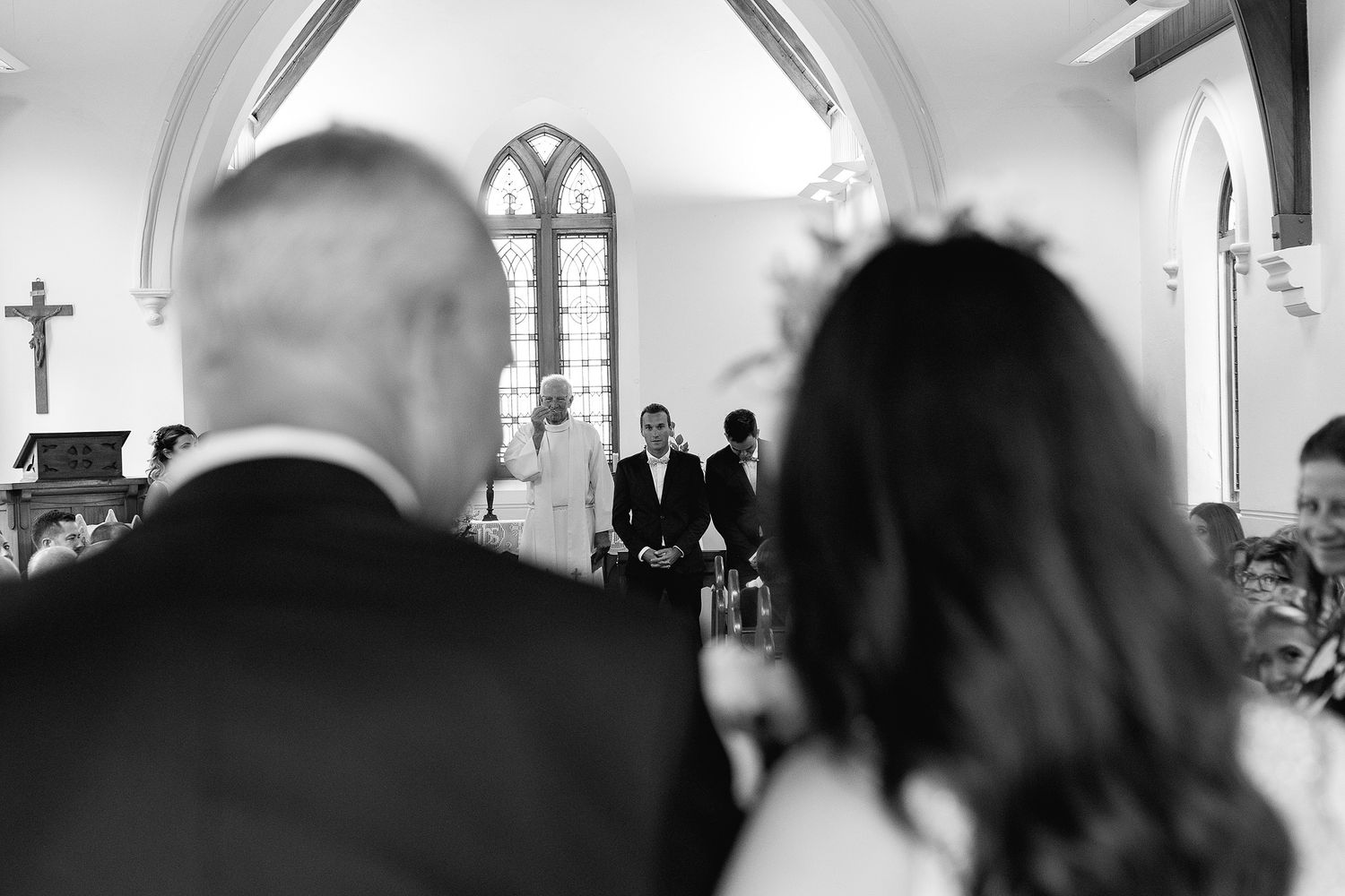 A black and white photo shows the interior of a church with multiple art frames hanging on the walls.