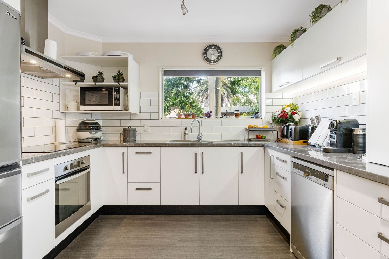 Sleek white modern kitchen with extensive countertops, integrated appliances, and minimalist cabinetry design.
