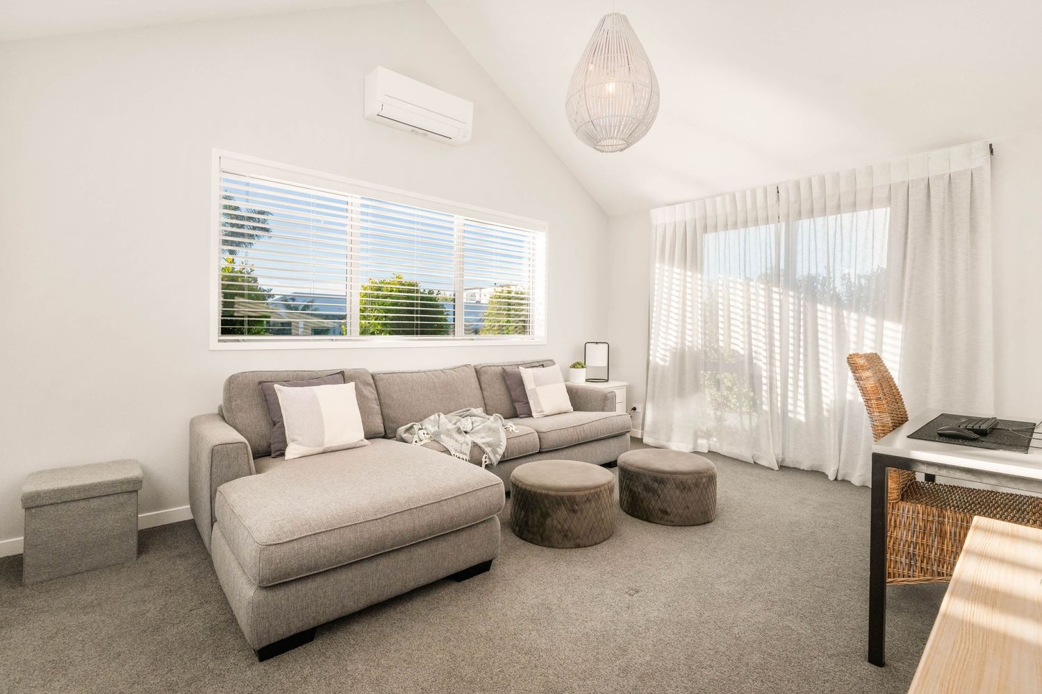 Modern living room with grey sofa, white walls, and natural lighting from large windows.