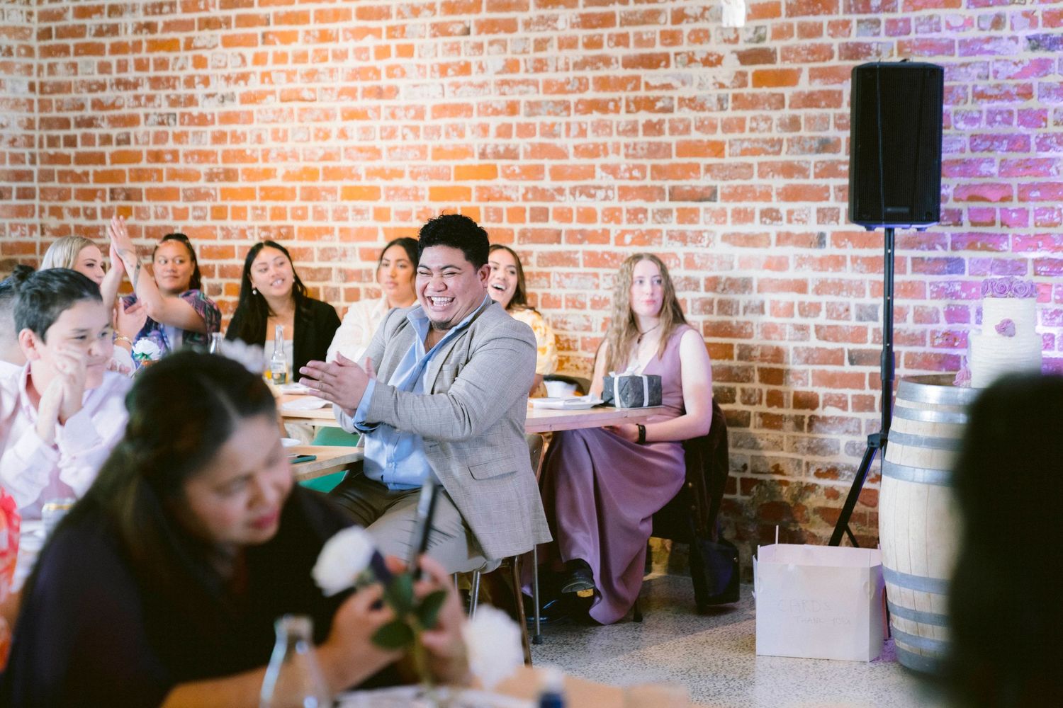 People seated at tables in a rustic brick-walled venue during a social gathering event.