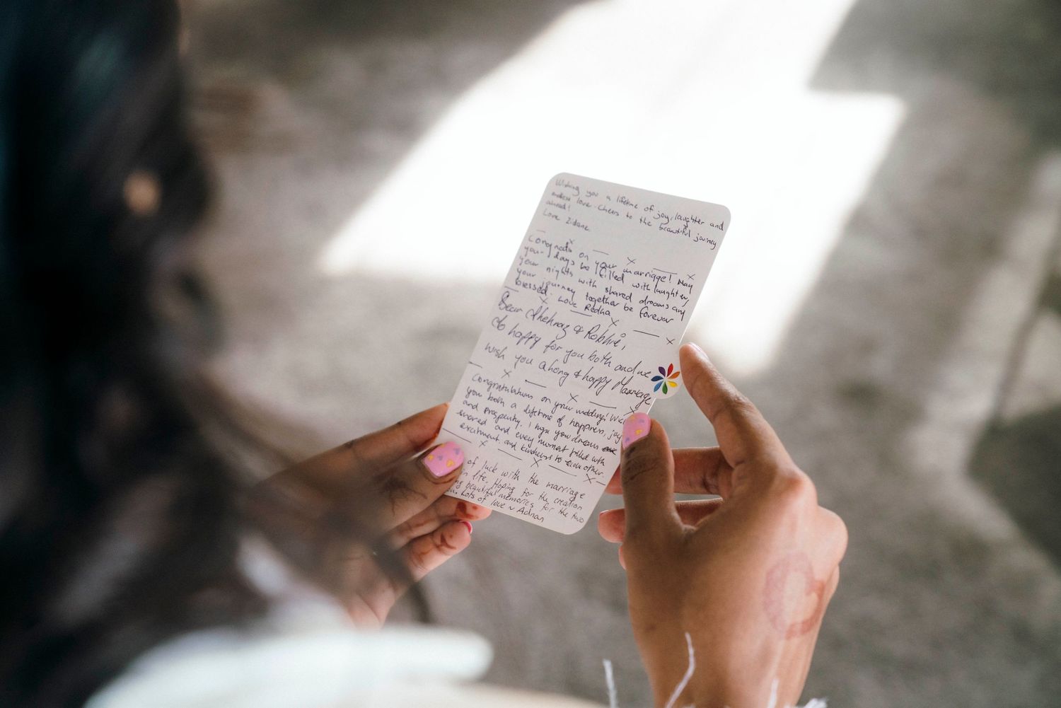Hands holding handwritten vows on paper in natural lighting.