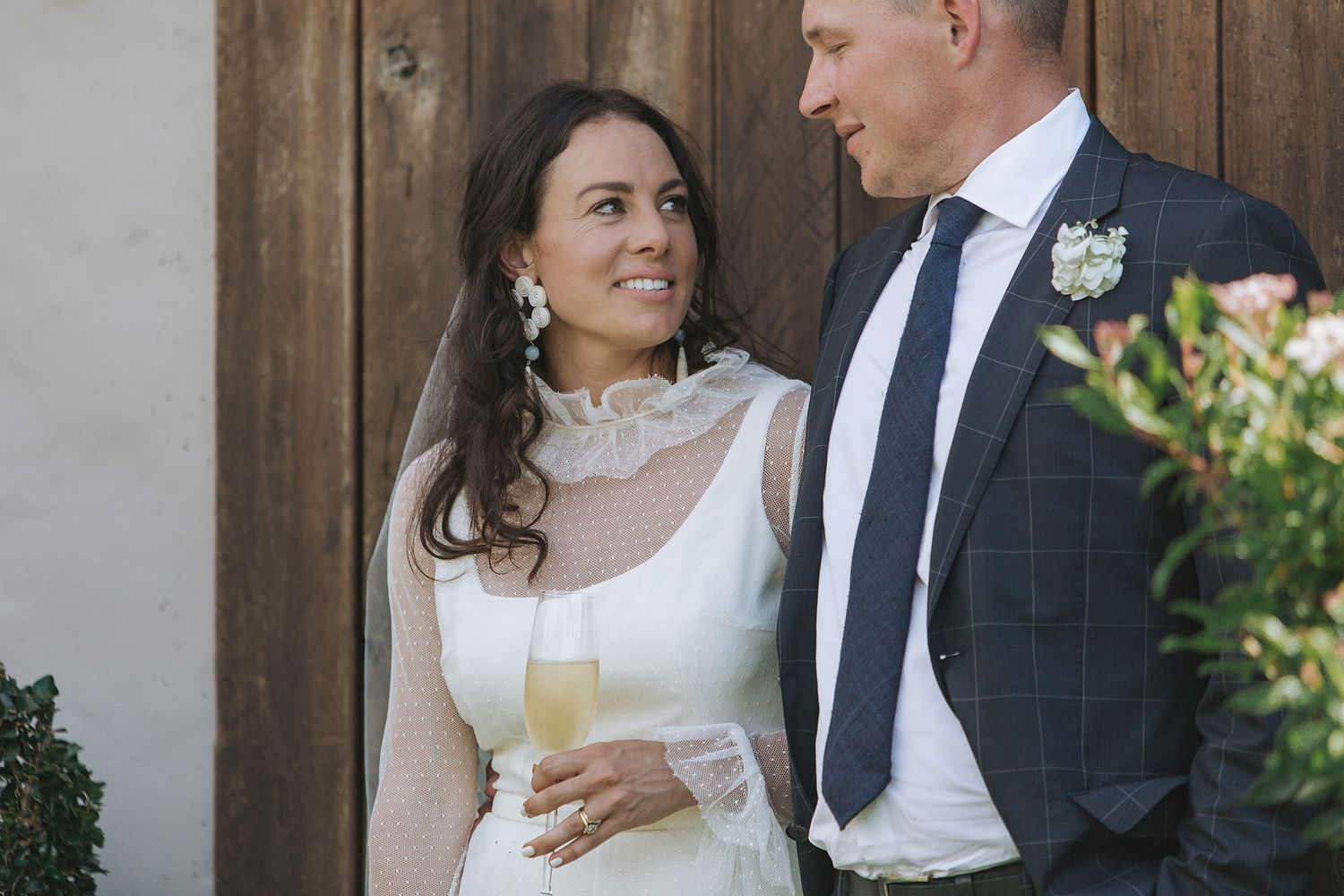 A bride in a classic white dress and groom in dark suit share intimate moments in gardens during their wedding day.