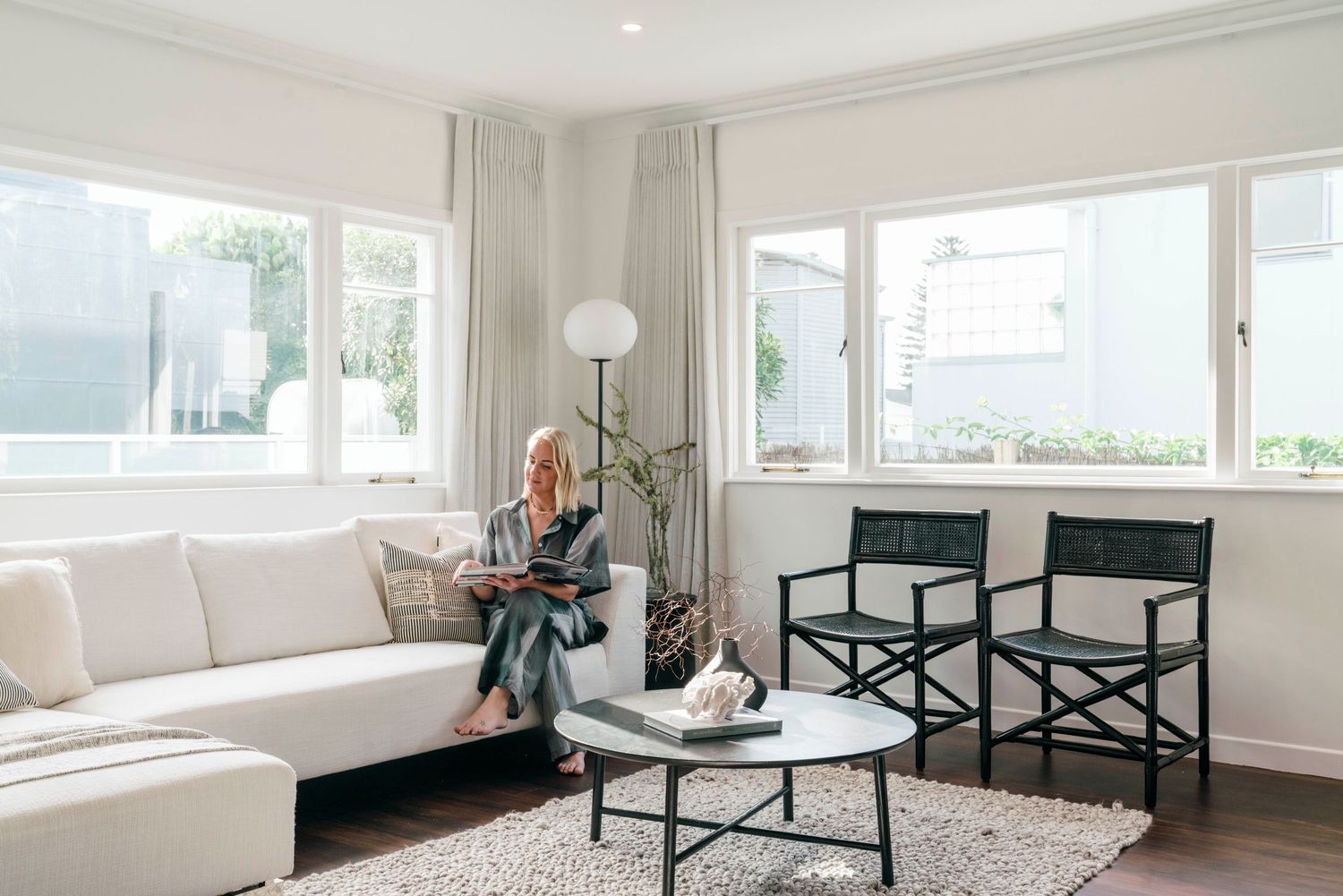 Minimalist living area featuring a white sectional sofa and panoramic windows.