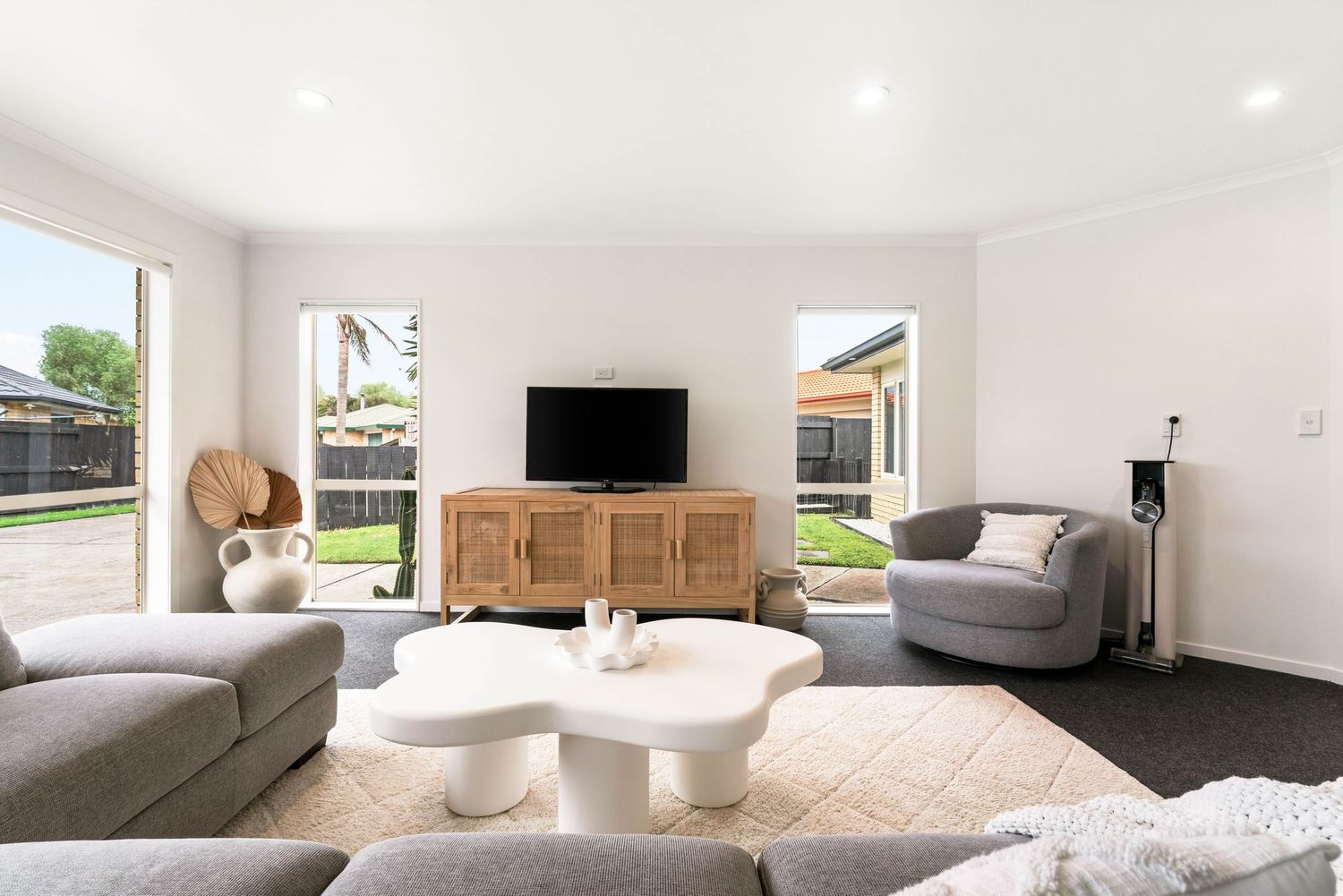 Contemporary living room with gray sofas, wooden media console and unique circular coffee tables.