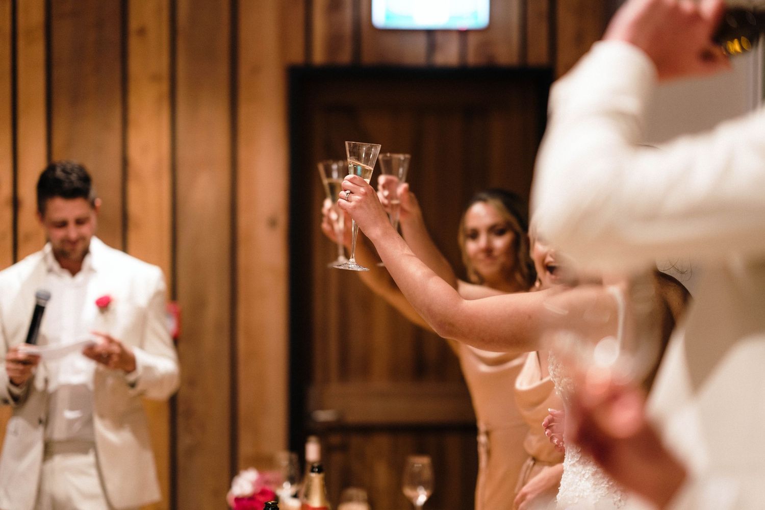 Wedding reception celebration in rustic wood-paneled venue with dancing.