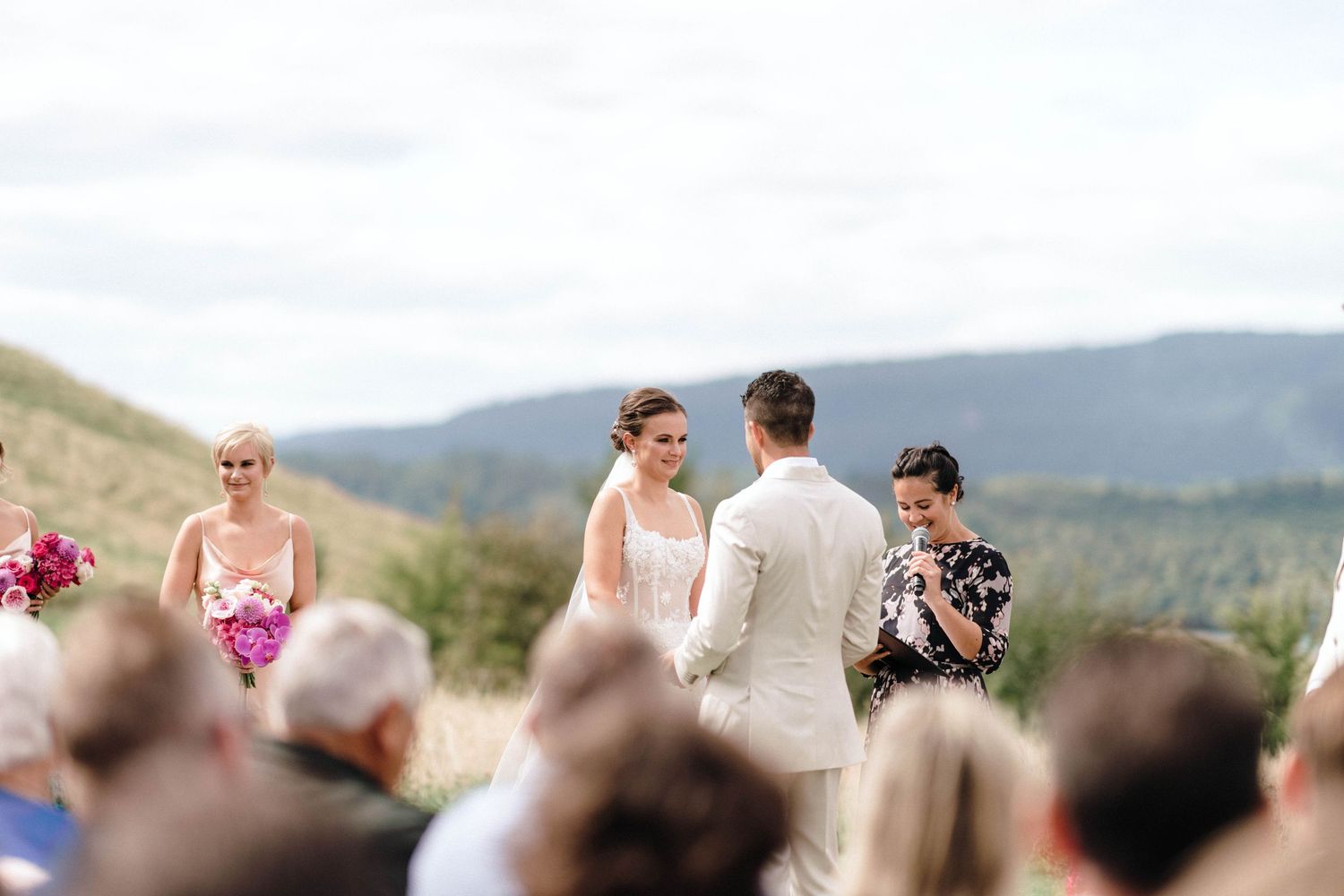 Outdoor wedding ceremony with mountain backdrop and guests in attendance.