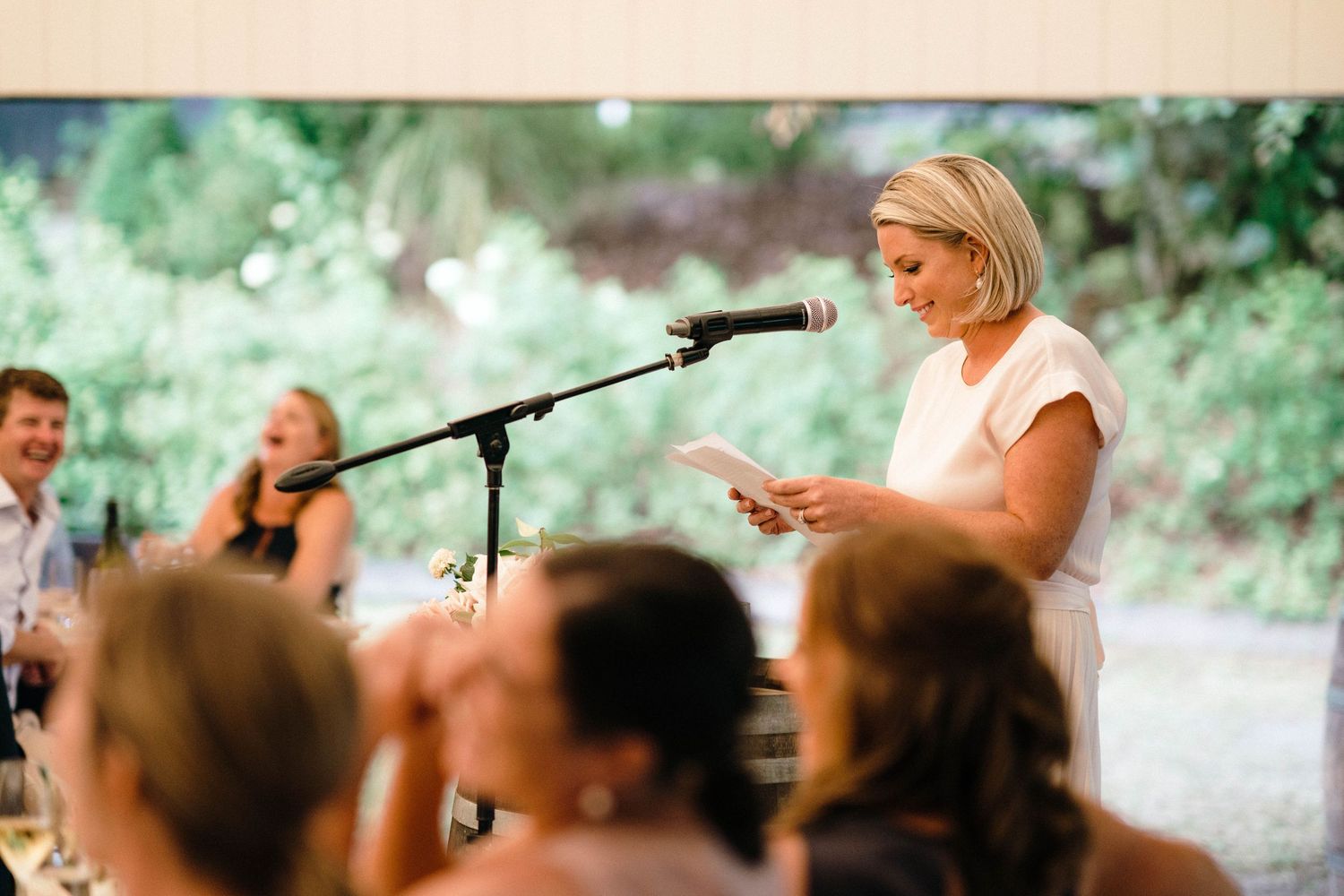 Speaker delivering a speech at an outdoor wedding reception with microphone stand.
