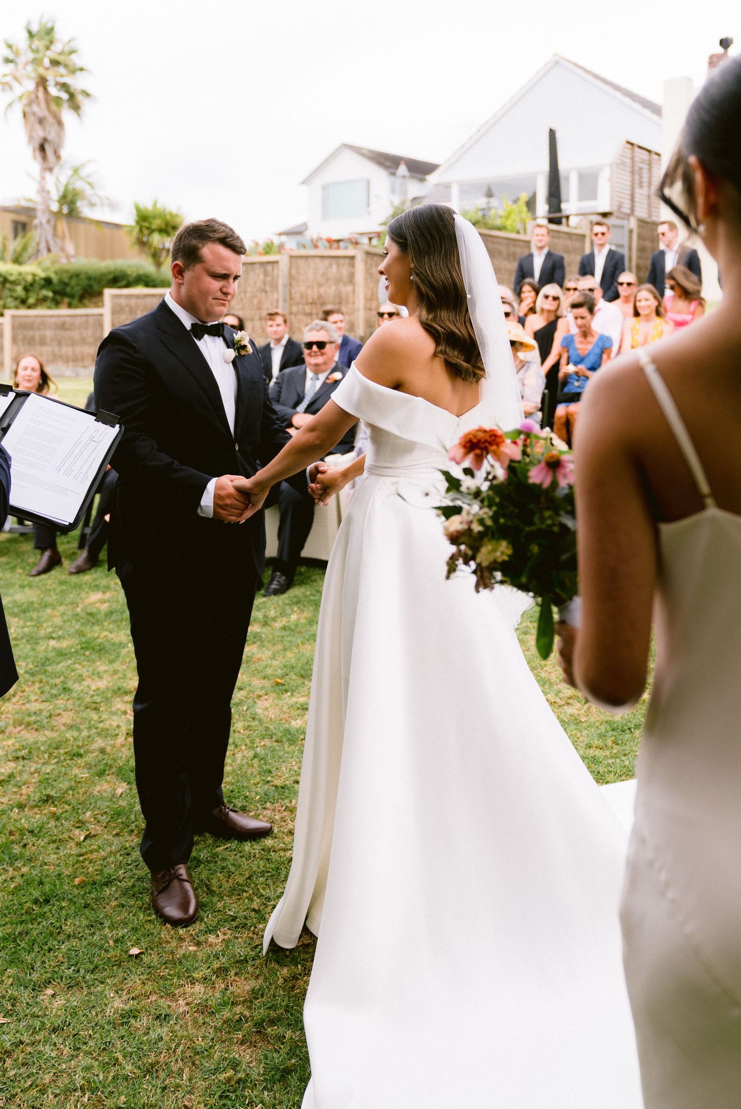 An outdoor wedding ceremony scene with guests watching the couple exchange vows.