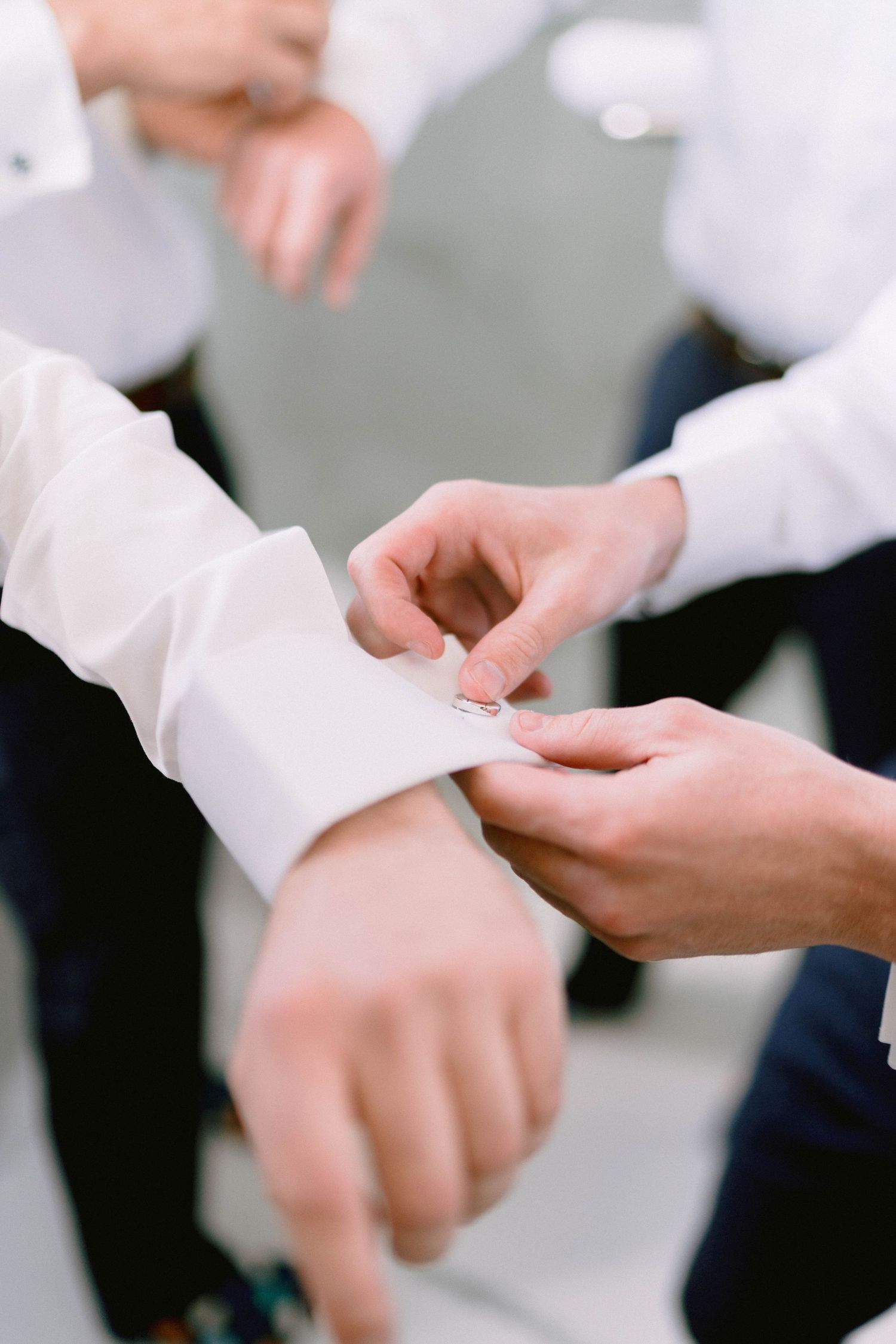 Hands adjusting a crisp white shirt cuff with delicate precision and care.