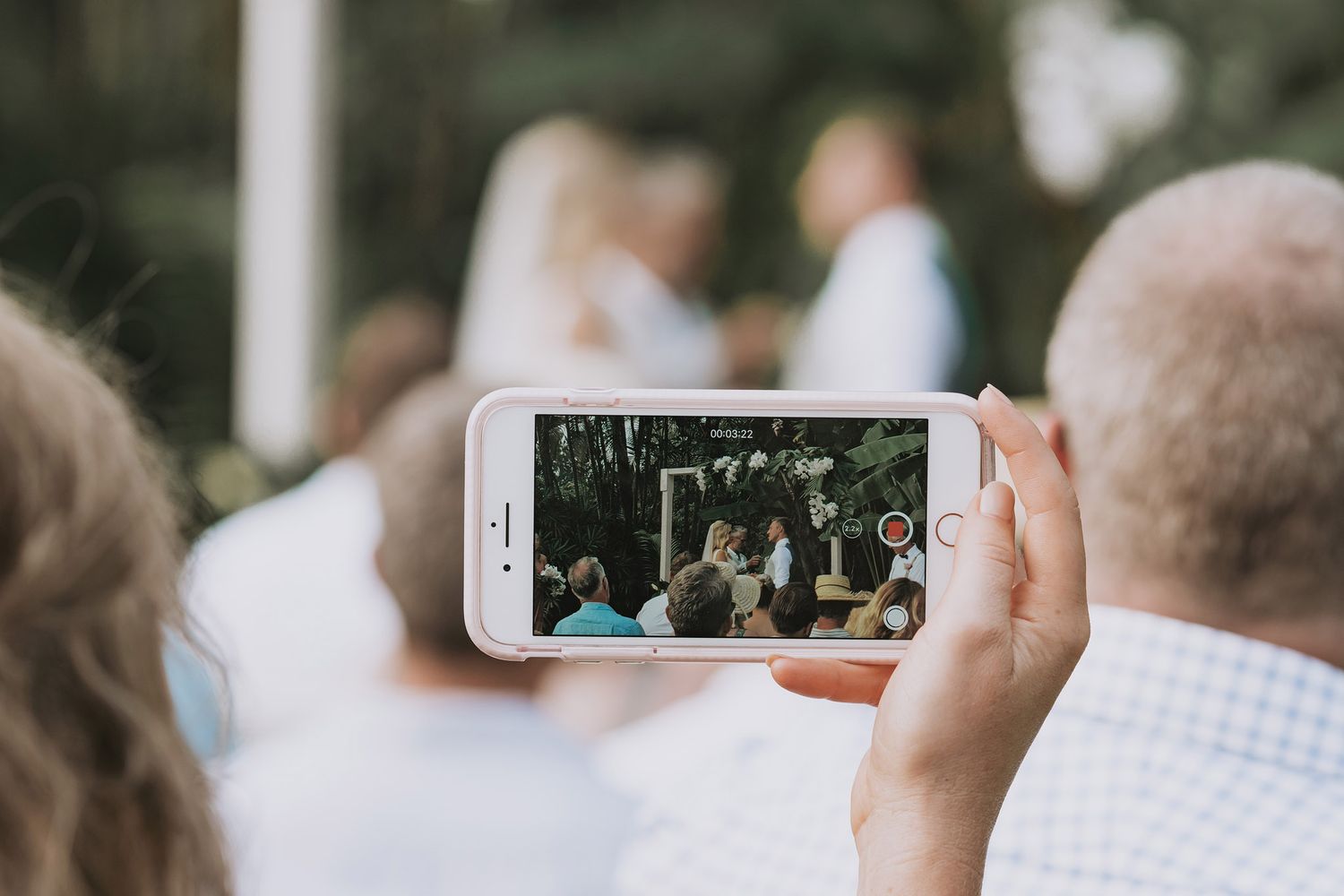 Someone capturing a wedding ceremony moment through their iPhone camera.
