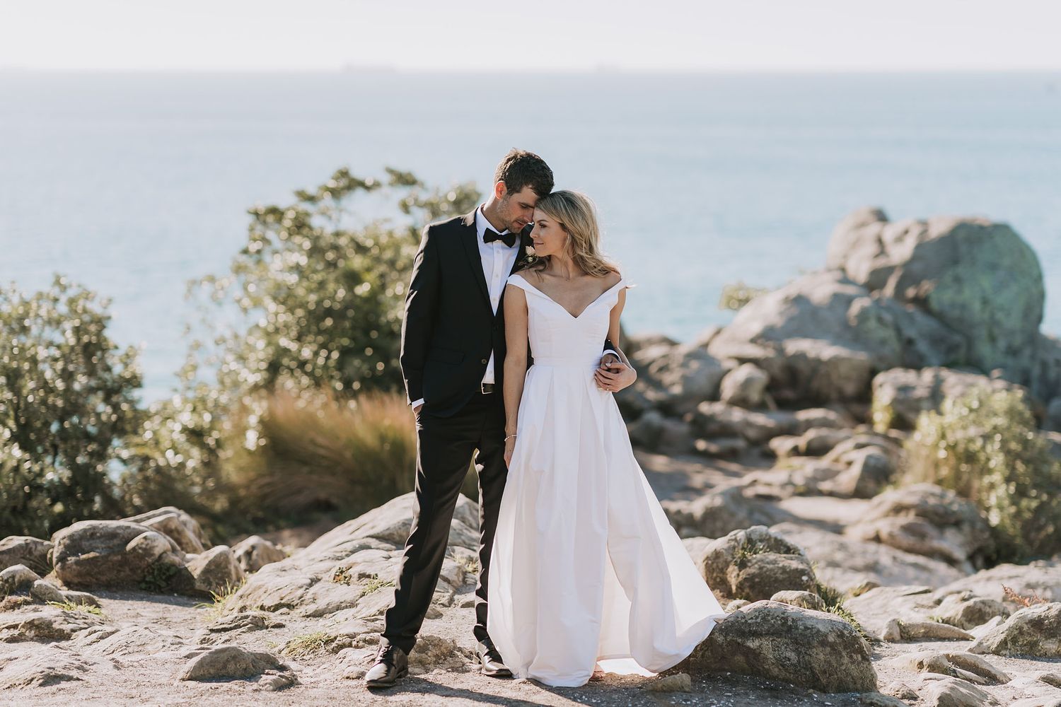 A couple poses against a scenic mountain backdrop during their wedding photoshoot in an outdoor setting.