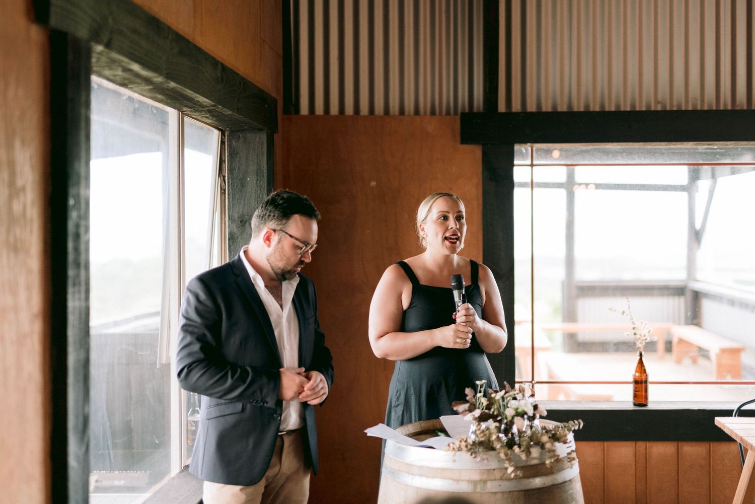 Wedding guests enjoying drinks and conversation in a rustic indoor venue.