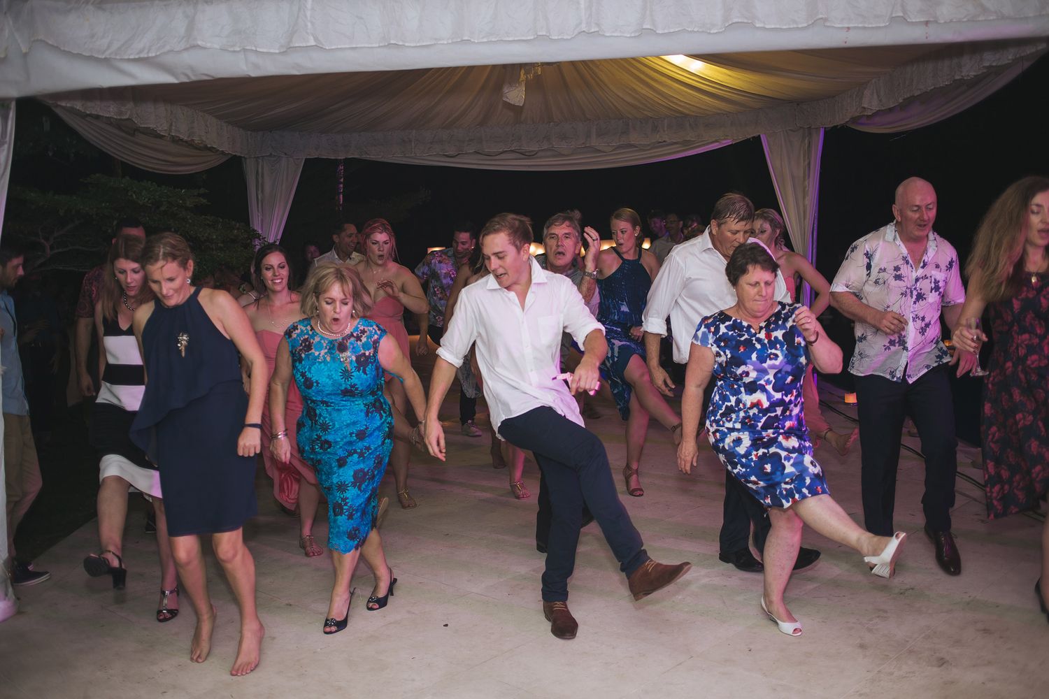 Wedding guests dancing and celebrating on the dance floor at an evening reception.