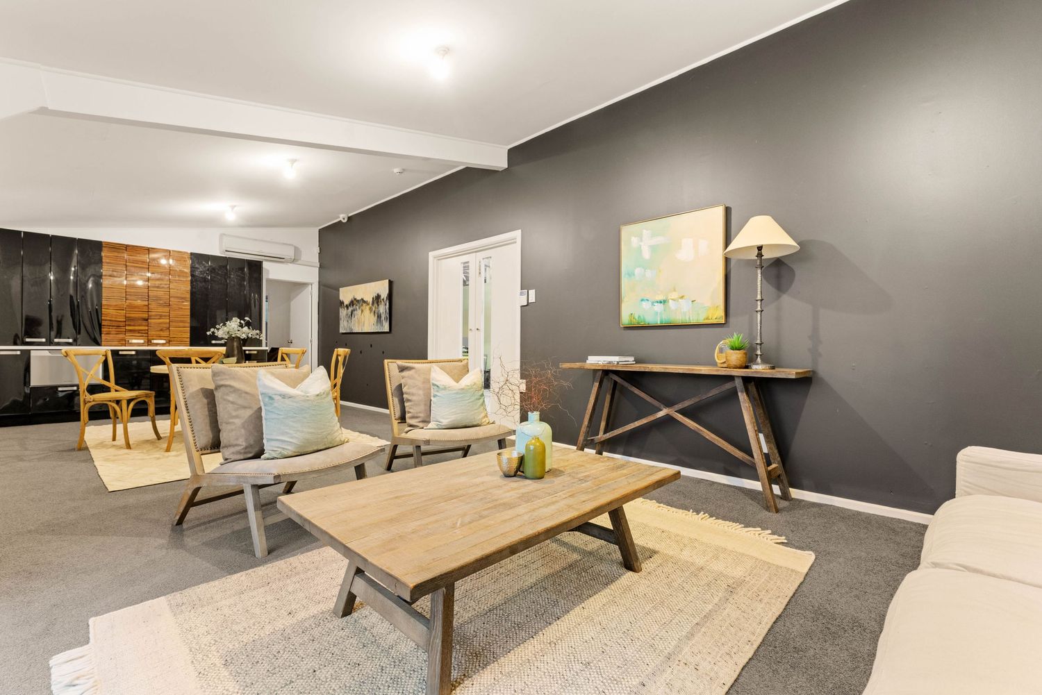 Modern living area with dark gray walls, wooden coffee table, and mid-century modern furniture on neutral rug.