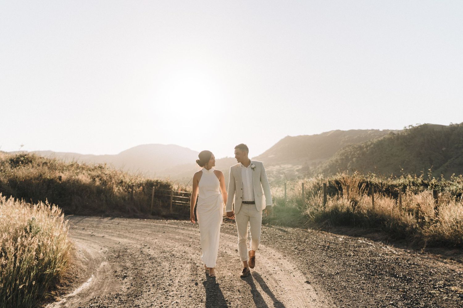 Wedding party walking along a scenic path during golden hour with mountains in the background.