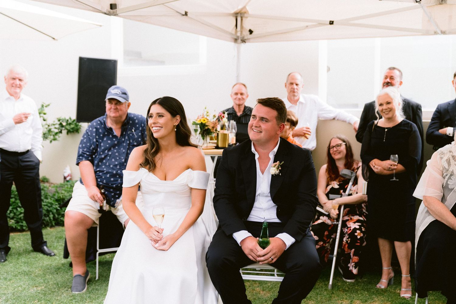 Wedding reception under a white tent with guests enjoying the celebration.