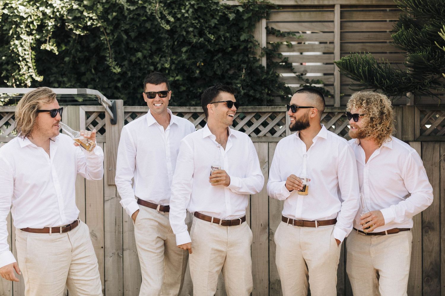 Group of people in matching white shirts and khaki pants enjoying drinks at an outdoor gathering.