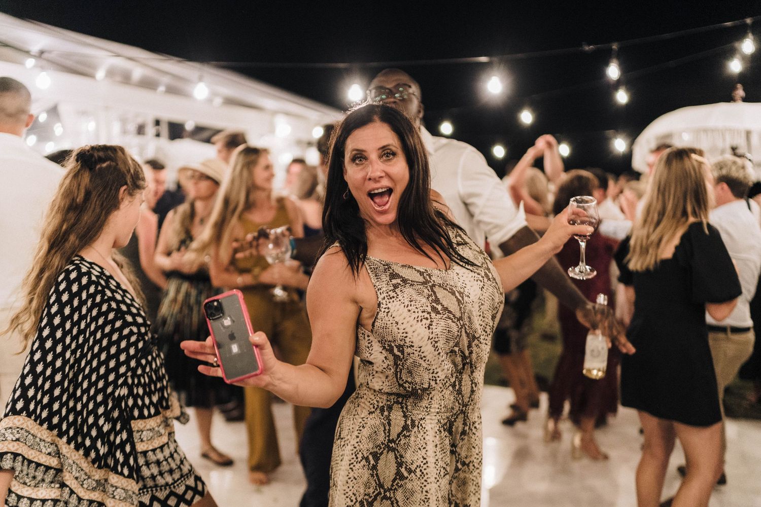 People dancing and having fun at a lively indoor party with string lights and a festive atmosphere.