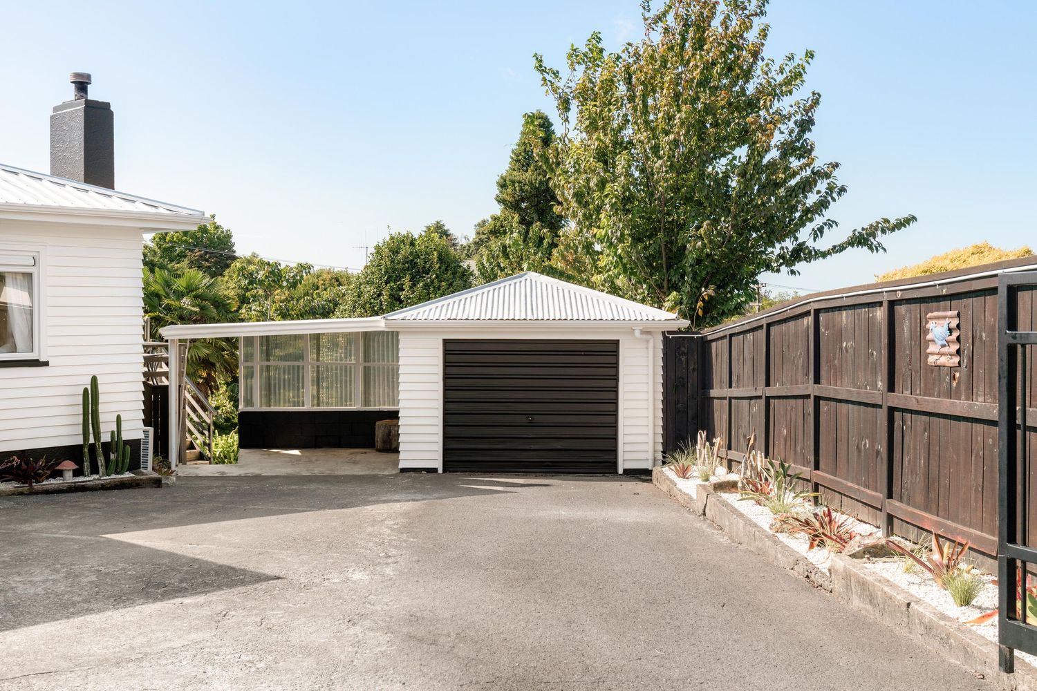 Panoramic view of self storage units with black garage doors and white exterior walls arranged in a long row.