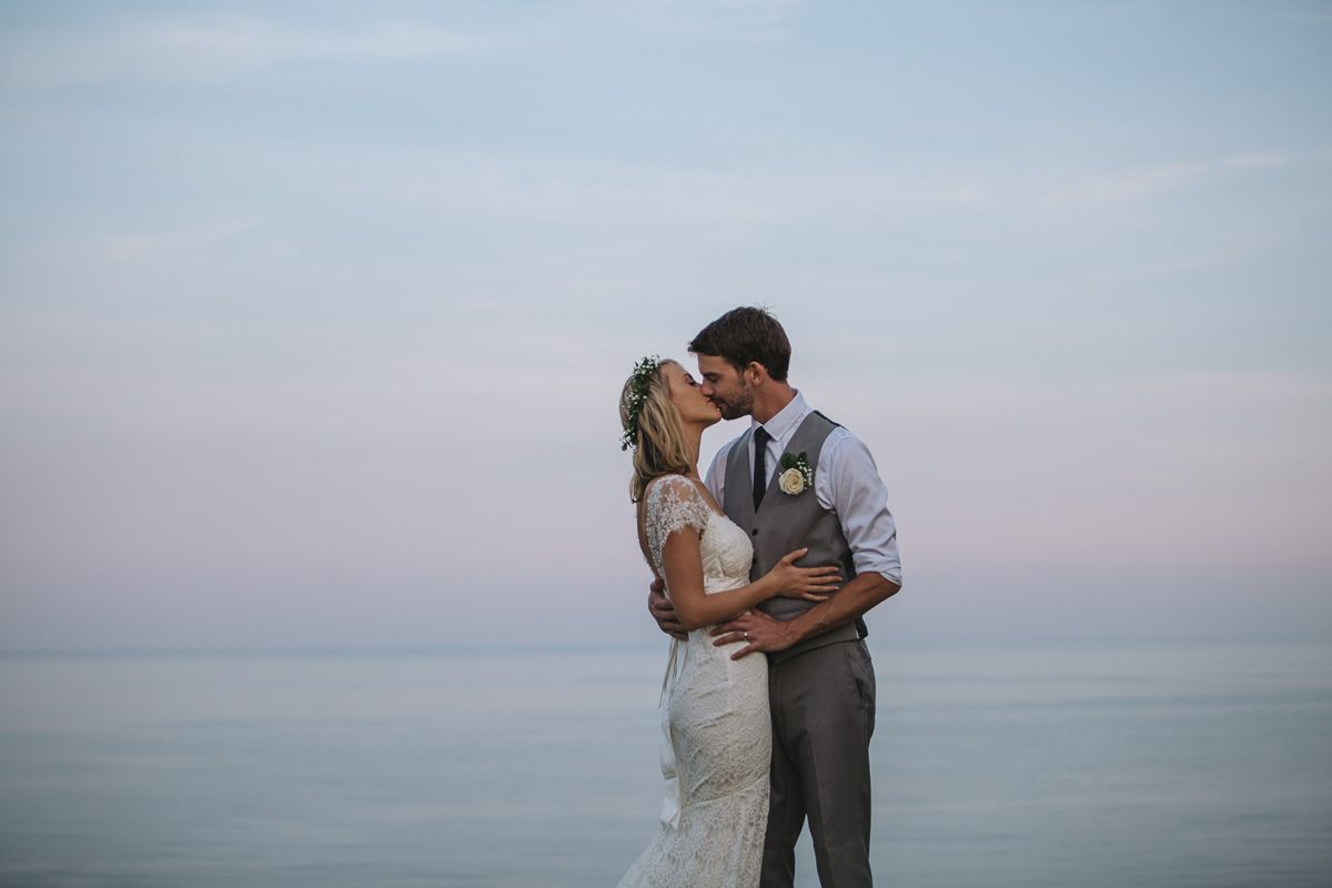 Romantic beach wedding portraits with couple sharing intimate moments against ocean backdrop at sunset.