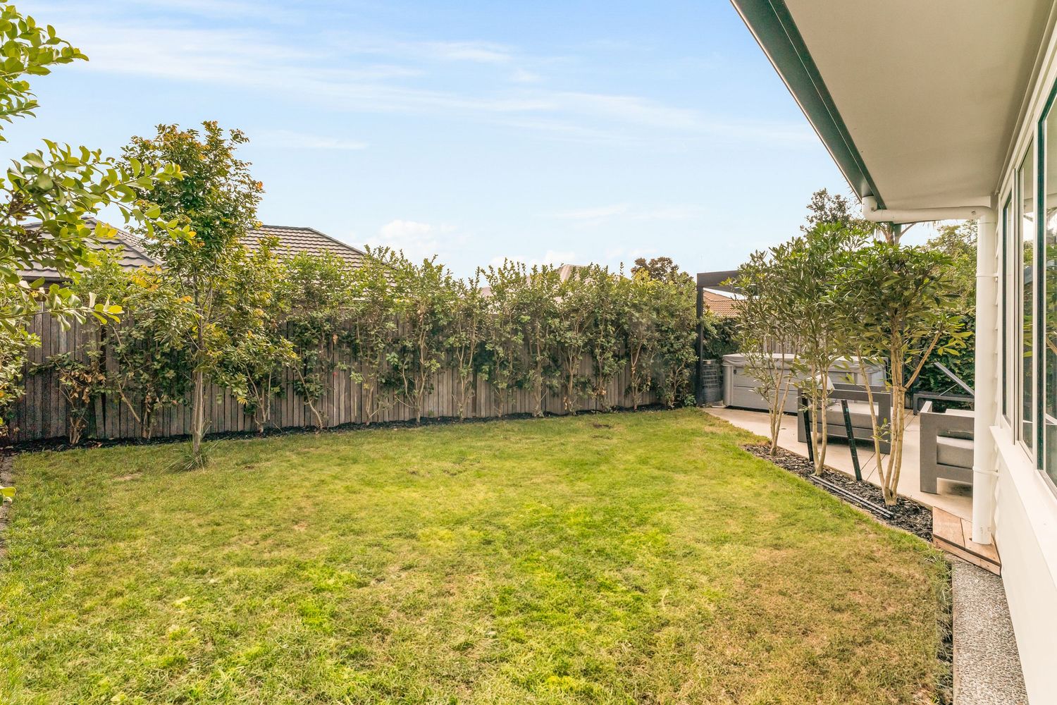 Panoramic view of a lush green backyard with rolling hills and trees in the background.