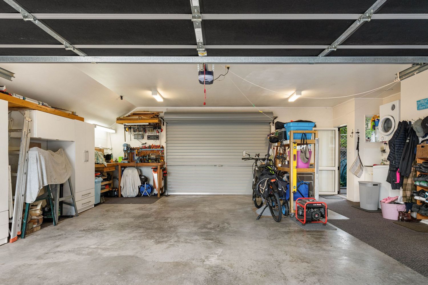 Spacious garage with concrete floor showing organized storage areas, shelving units, and recreational equipment.
