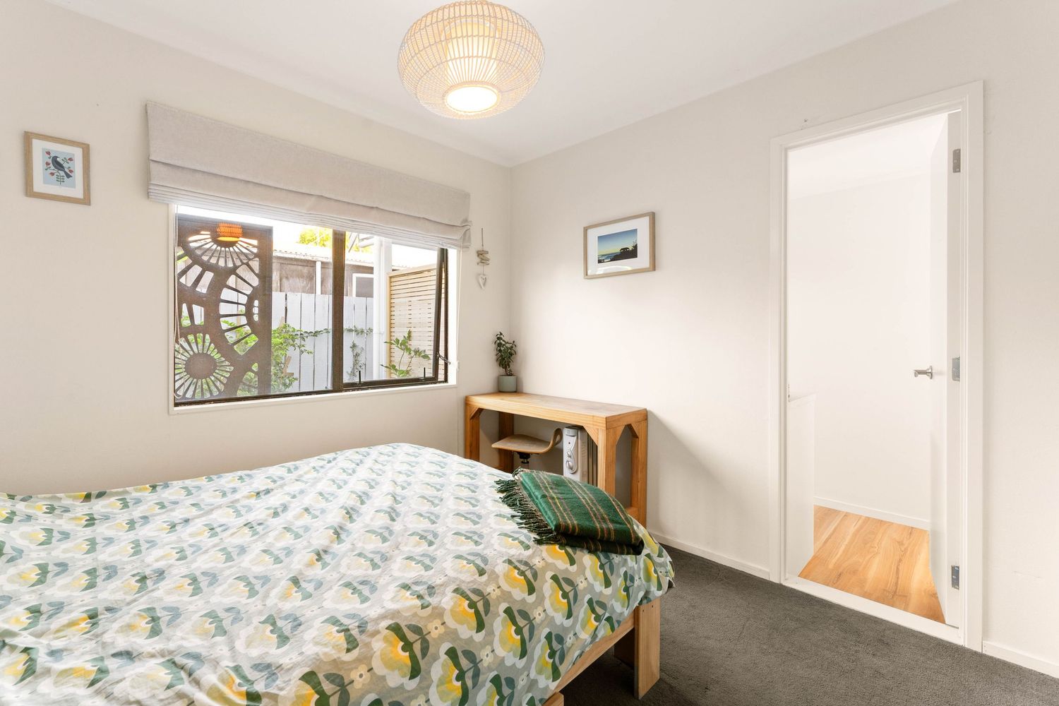Bright bedroom with geometric patterned bedding, wooden desk, and decorated white walls.