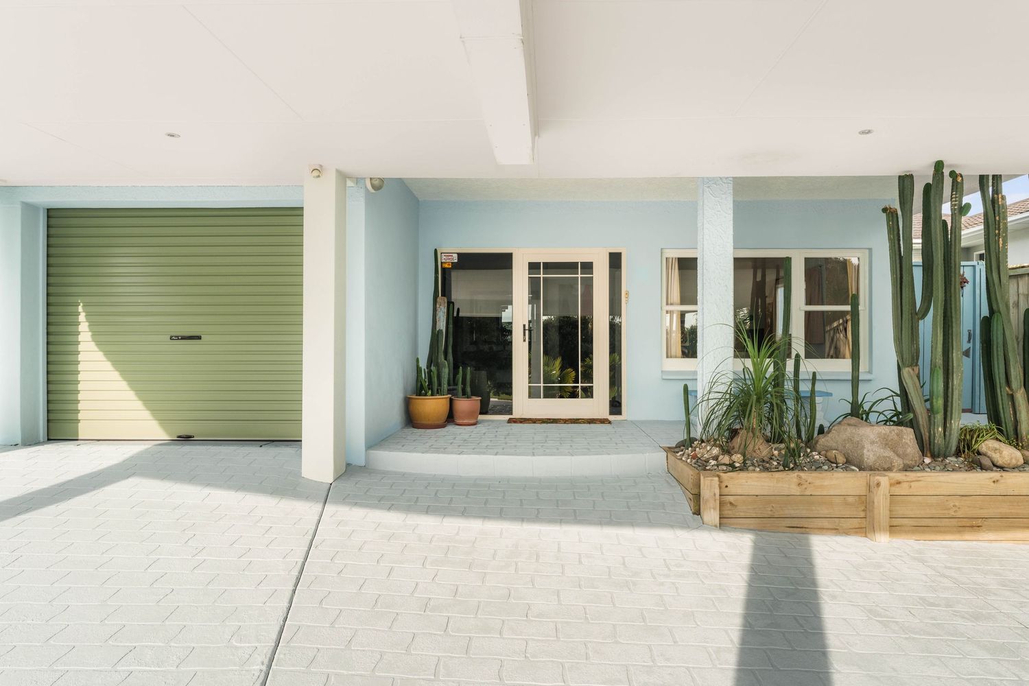 A series of tranquil walkways and paths with light green shutters and white walls leading to outdoor living spaces.