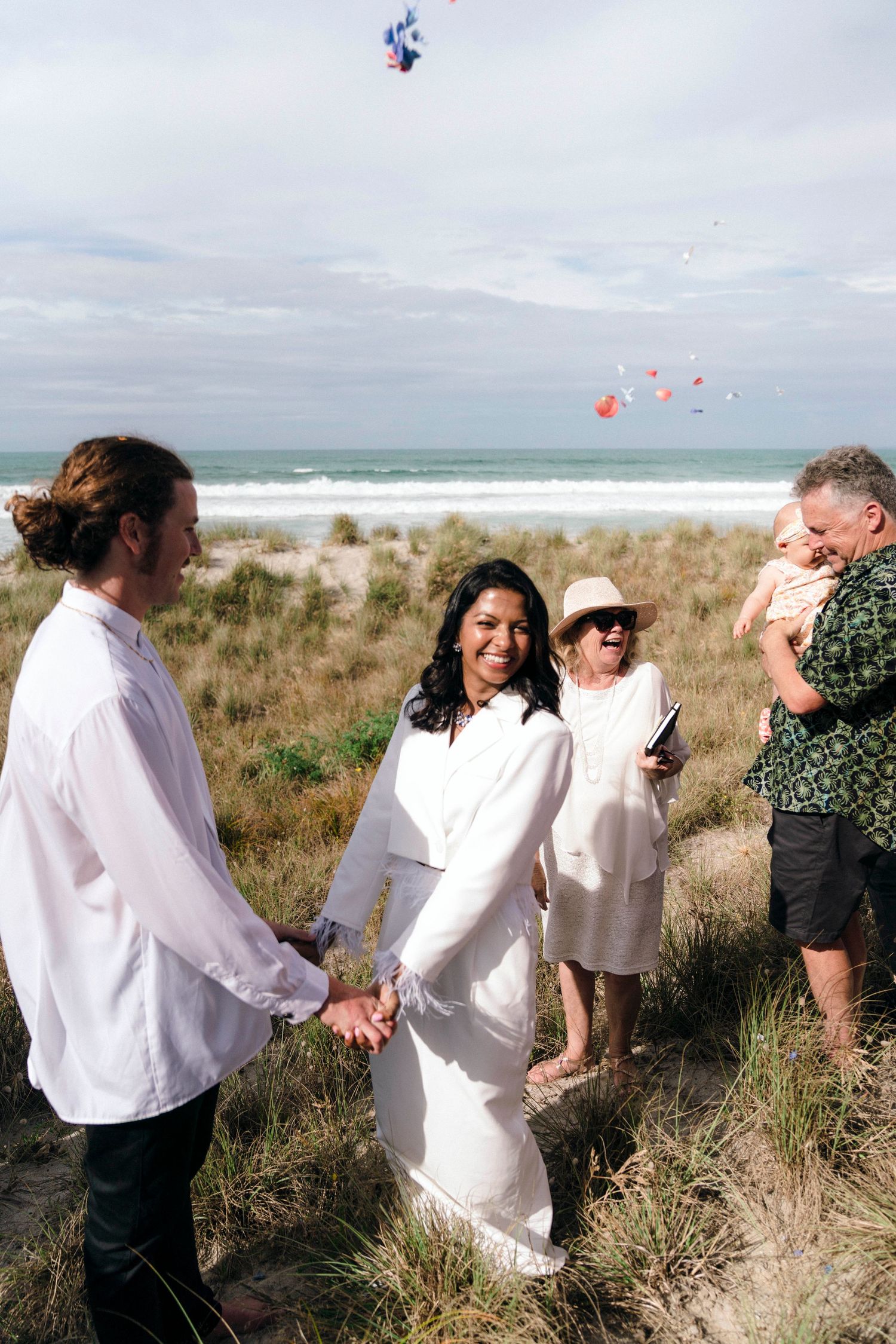 A beachside wedding ceremony with balloons floating in the sky over the ocean backdrop.