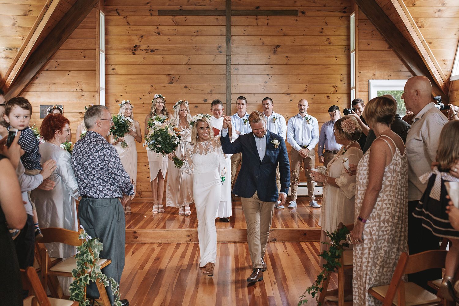 Wedding guests dancing and celebrating on a rustic wooden dance floor at a barn reception venue.
