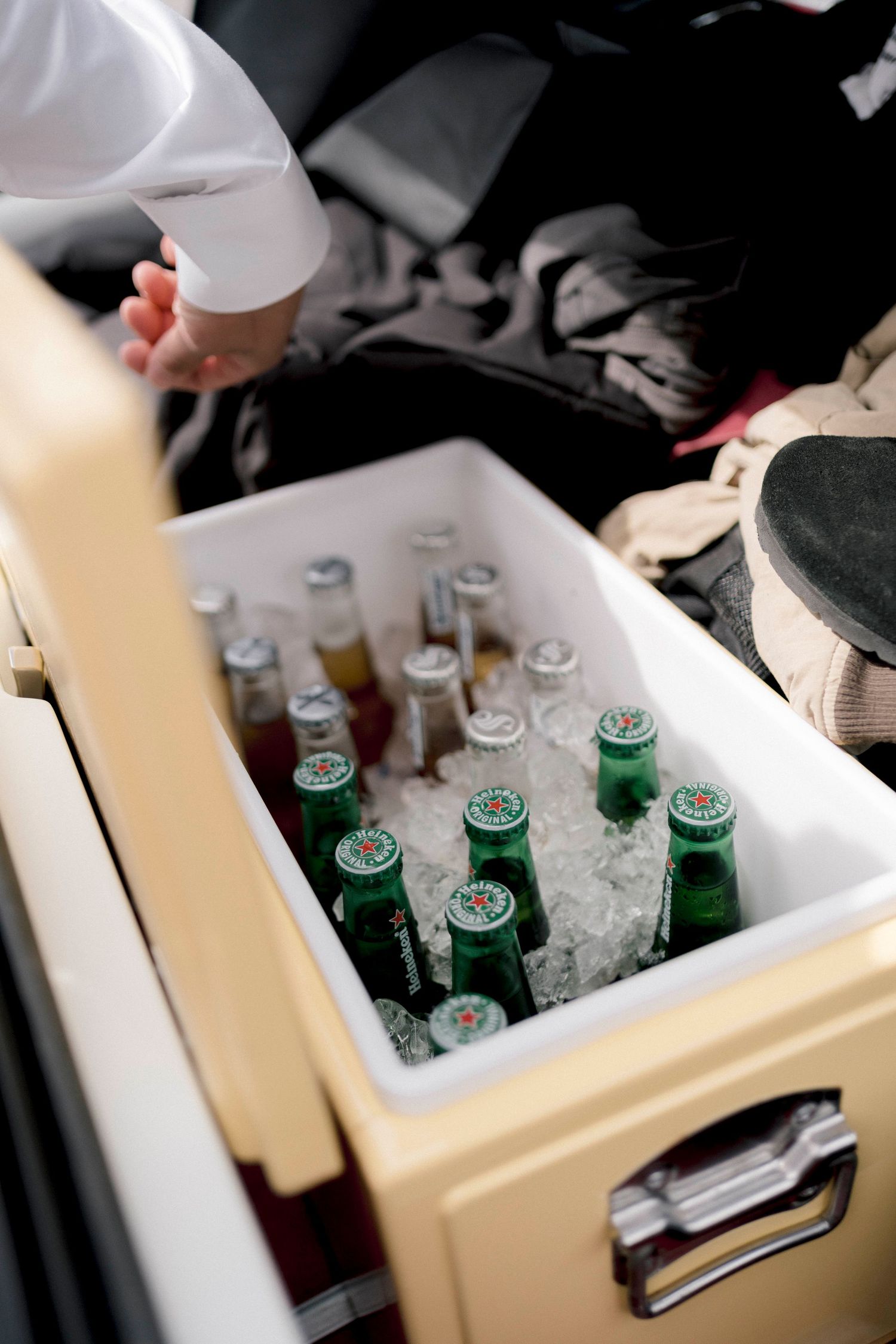 Beer bottles chilling in a vintage white cooler filled with ice.
