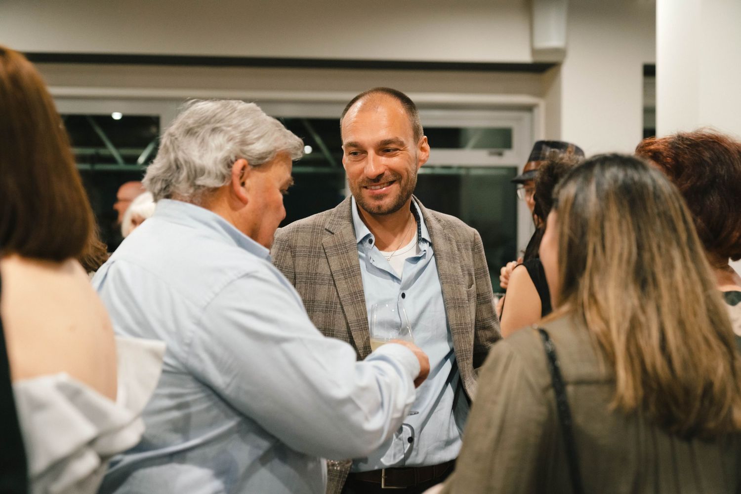Group of people mingling at a social gathering in an office space.