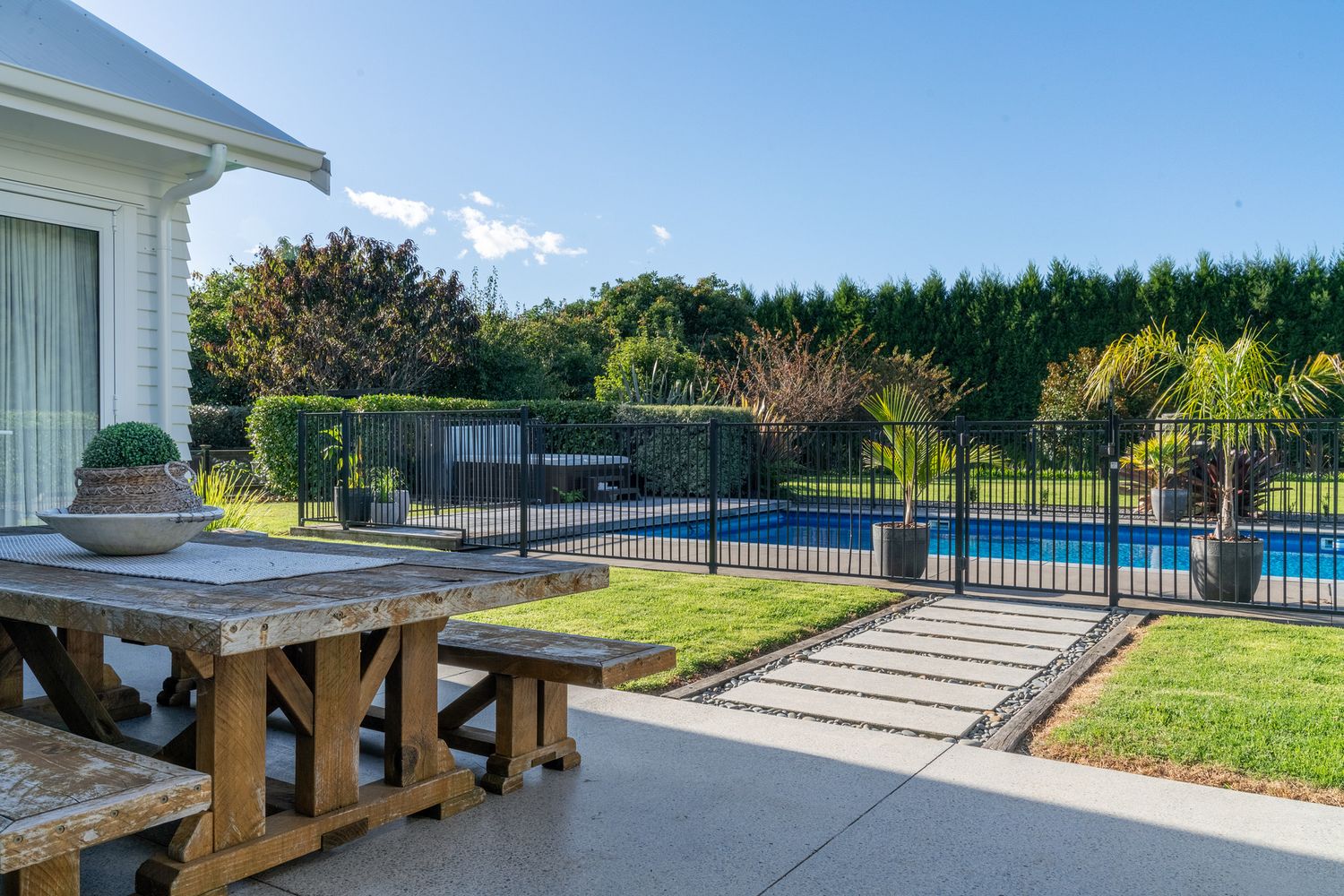 Outdoor patio area with wooden benches overlooking a fenced swimming pool.